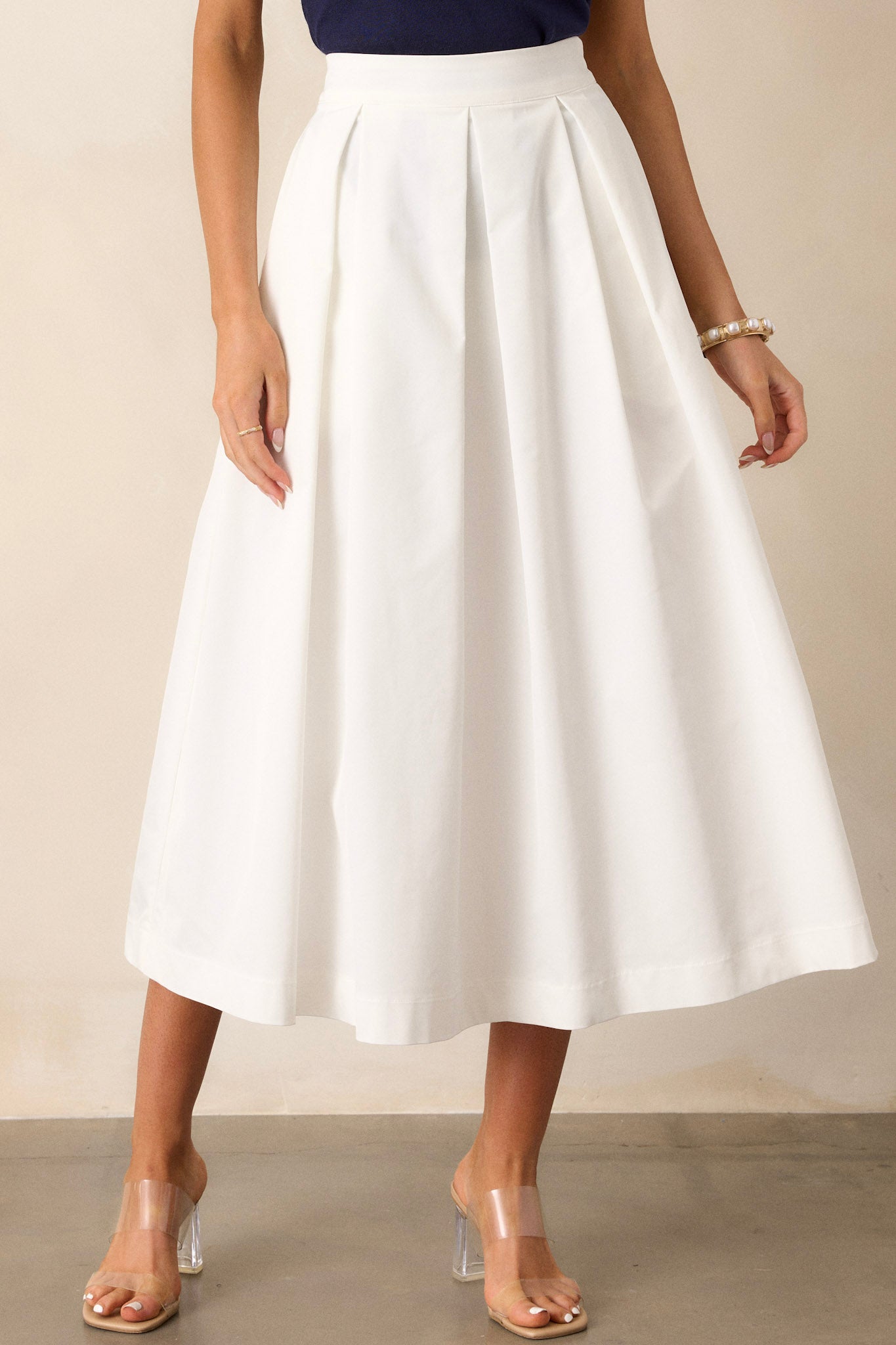 This white midi skirt features a high waisted design, a discrete side zipper, and a thick waistline.