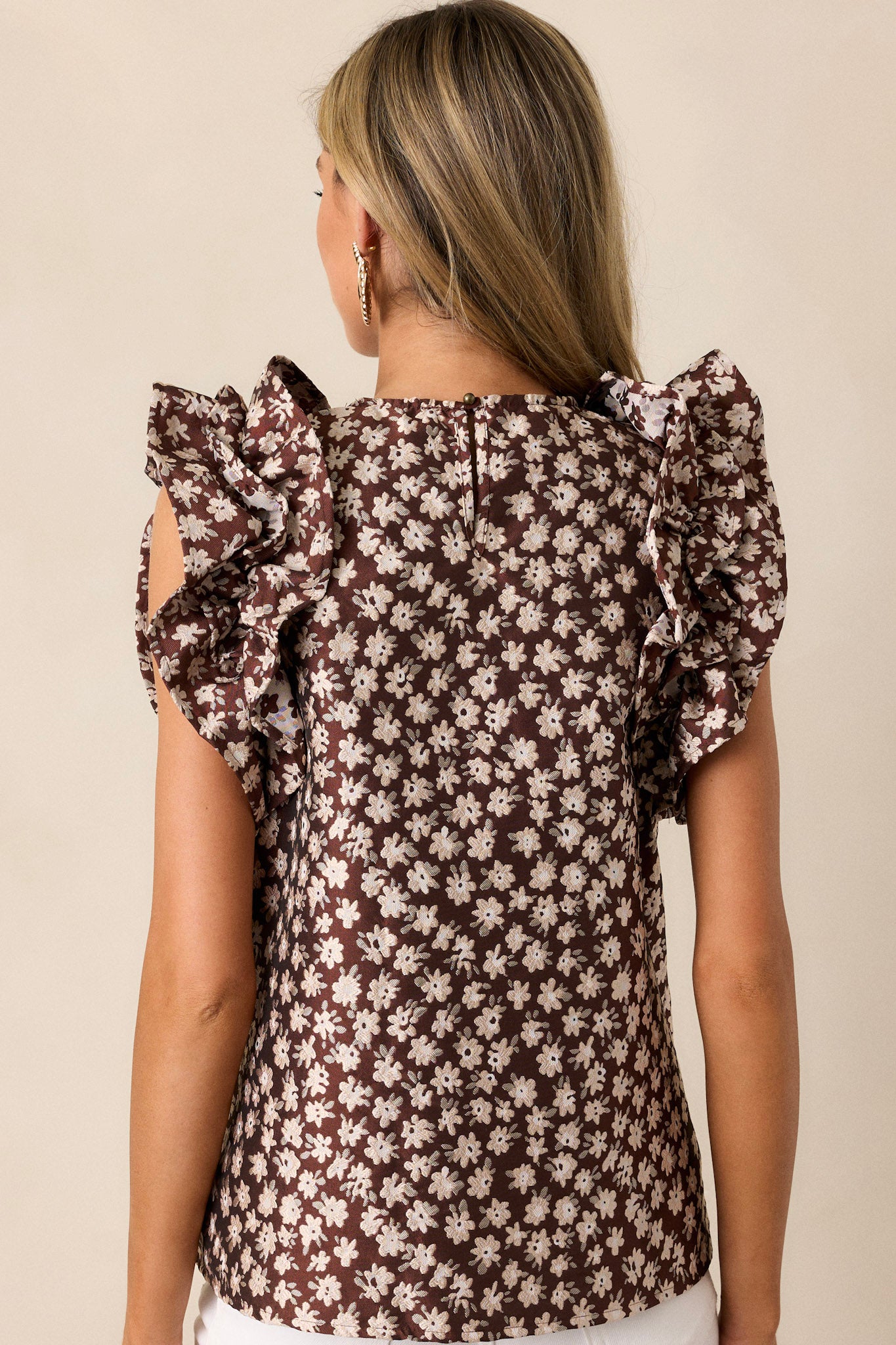 Back view of a brown floral top highlighting the overall fit and ruffled sleeveless design