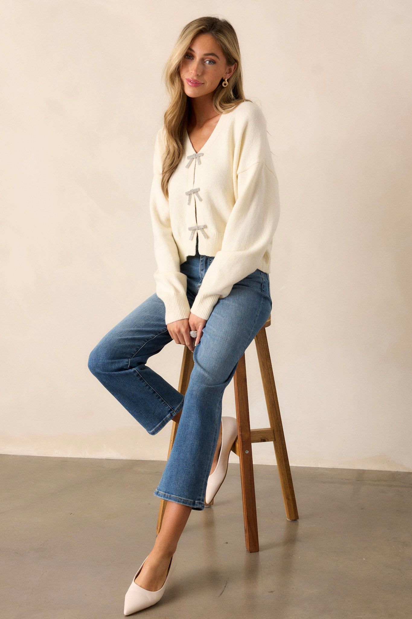 A full-length view of the ivory sweater featuring a v-neckline and a faux button front, showcasing its stylish silhouette and fit.