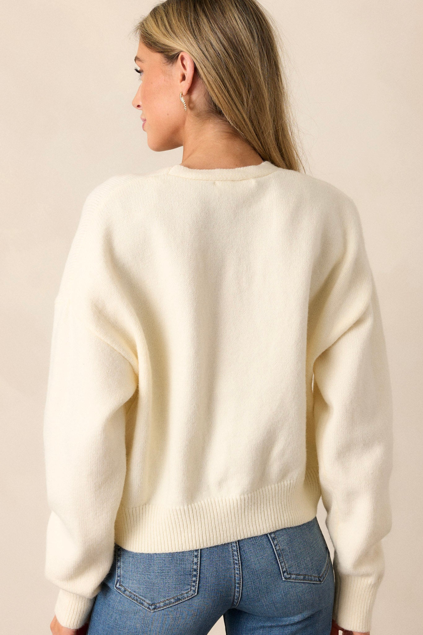 A view of the back of the ivory sweater, highlighting the simplicity of the design while showcasing the ribbed hems that continue from the front.