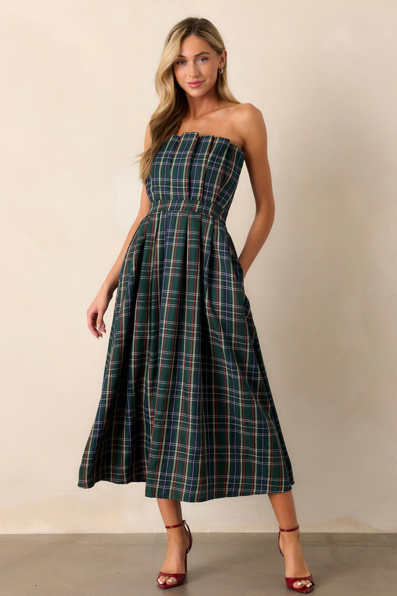 A full-length view of the green plaid dress, showcasing the strapless design and pleated bodice that creates an elegant silhouette.