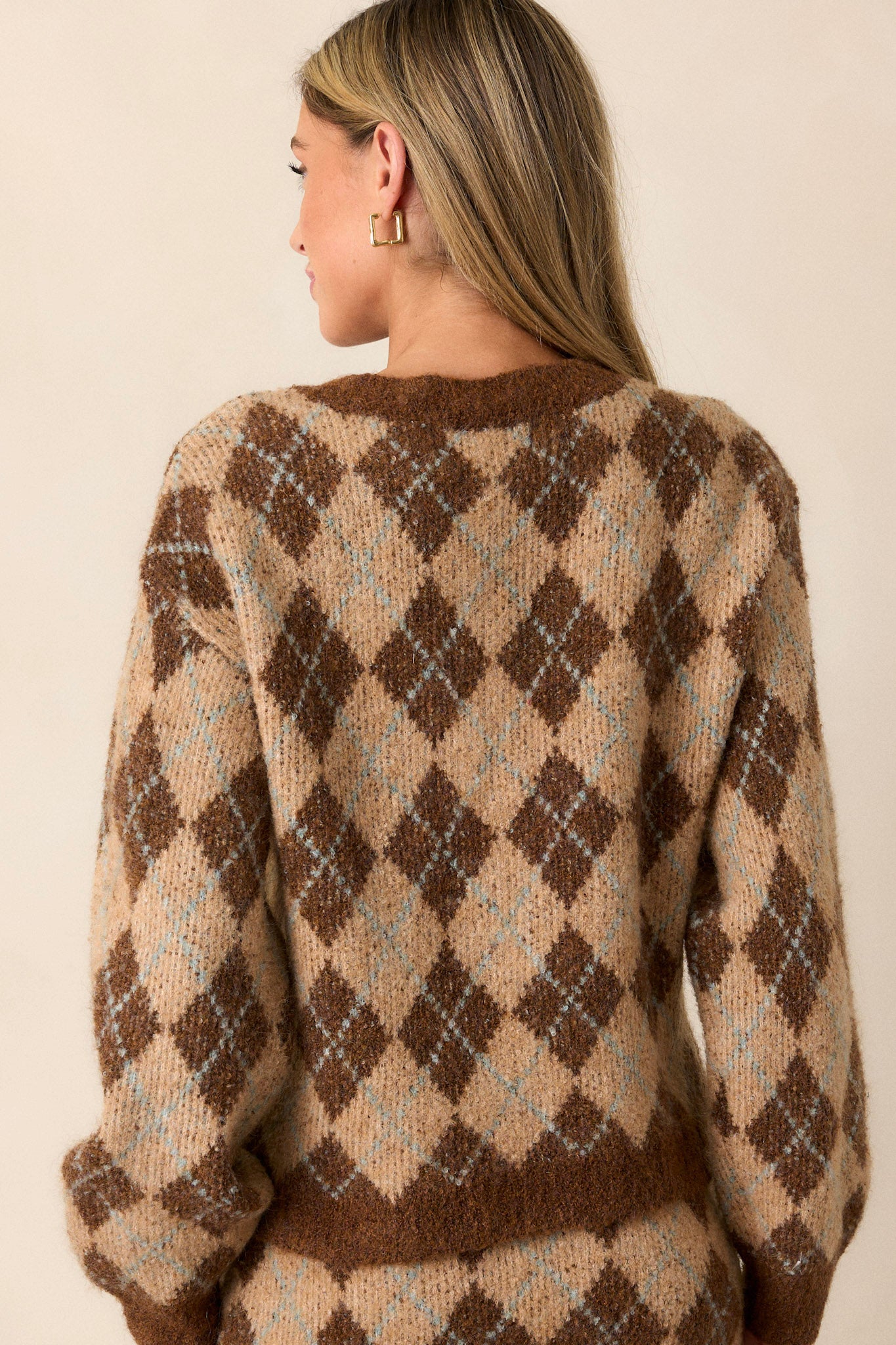 Back view of a cozy knit cardigan featuring a warm brown argyle pattern, functional textured brown buttons up the front, a v-neckline, and a relaxed fit.