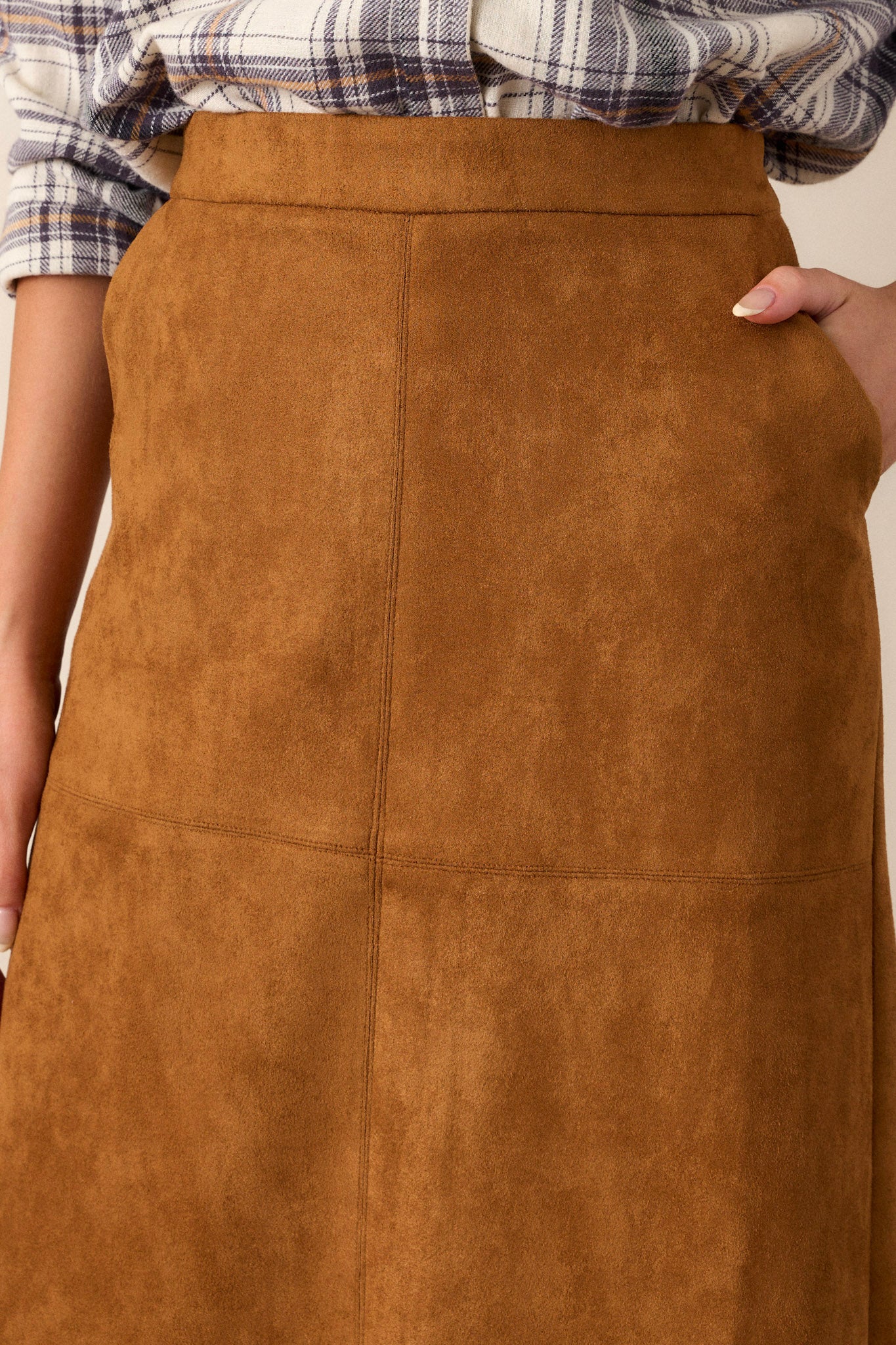 Close up of the faux suede material, functional pockets, and waistline of this A-line midi skirt.