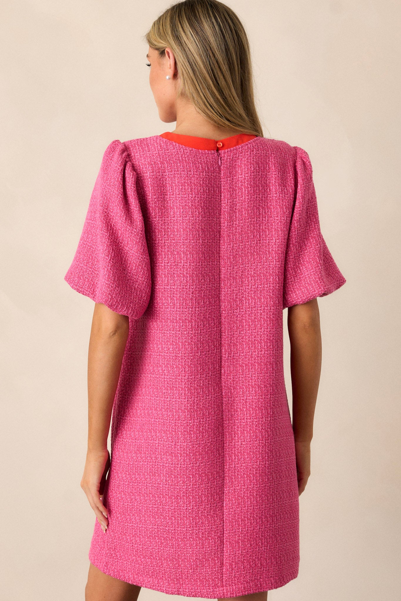 Back view of the pink tweed dress showcasing the discrete back zipper and the overall relaxed fit of the dress, along with a subtle view of the elastic cuffed short sleeves.