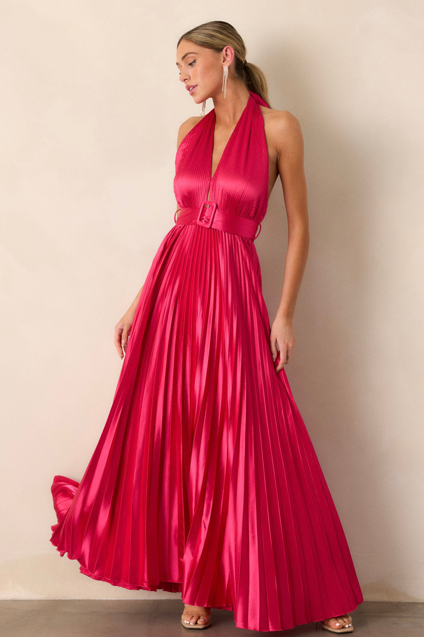 Action shot of the magenta pink dress displaying the flow and movement of the pleated fabric, highlighting the halter neck tie and the cinched waist with the functional belt.