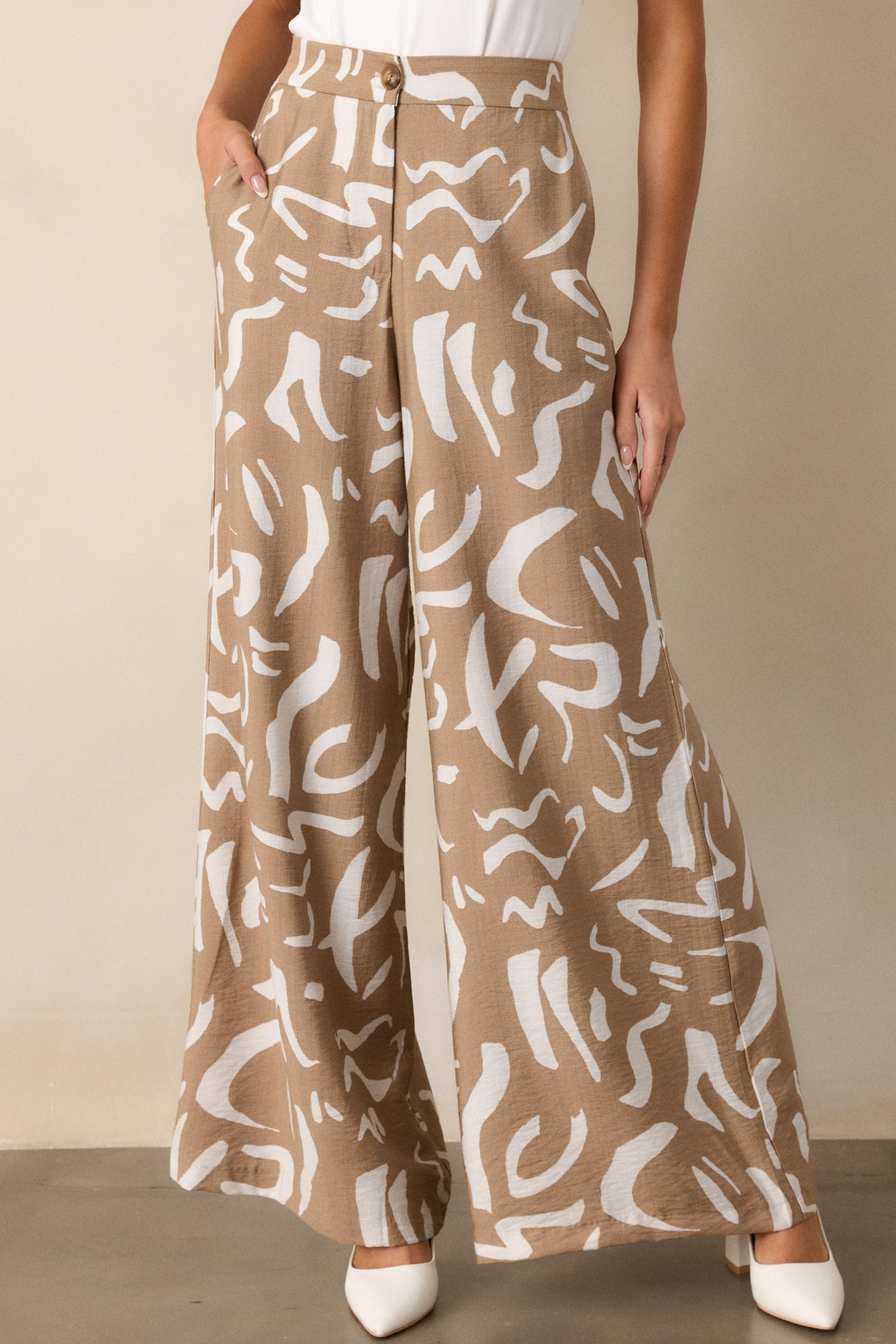 Detailed view of the wide leg silhouette of camel pants, emphasizing the flowy fit and the bold abstract pattern on the fabric.