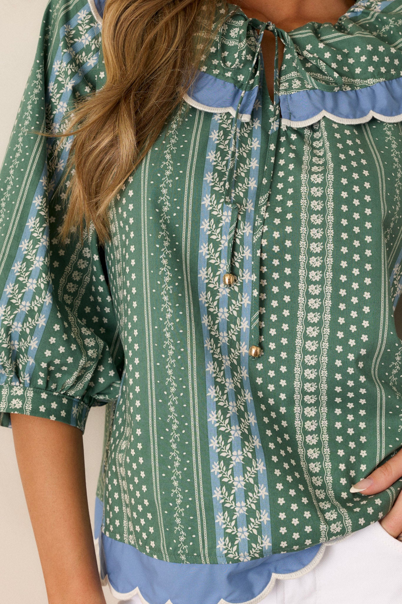 Close-up of the floral stripe print on the green top, emphasizing the texture and fine details of the scallop collar and cuffs.