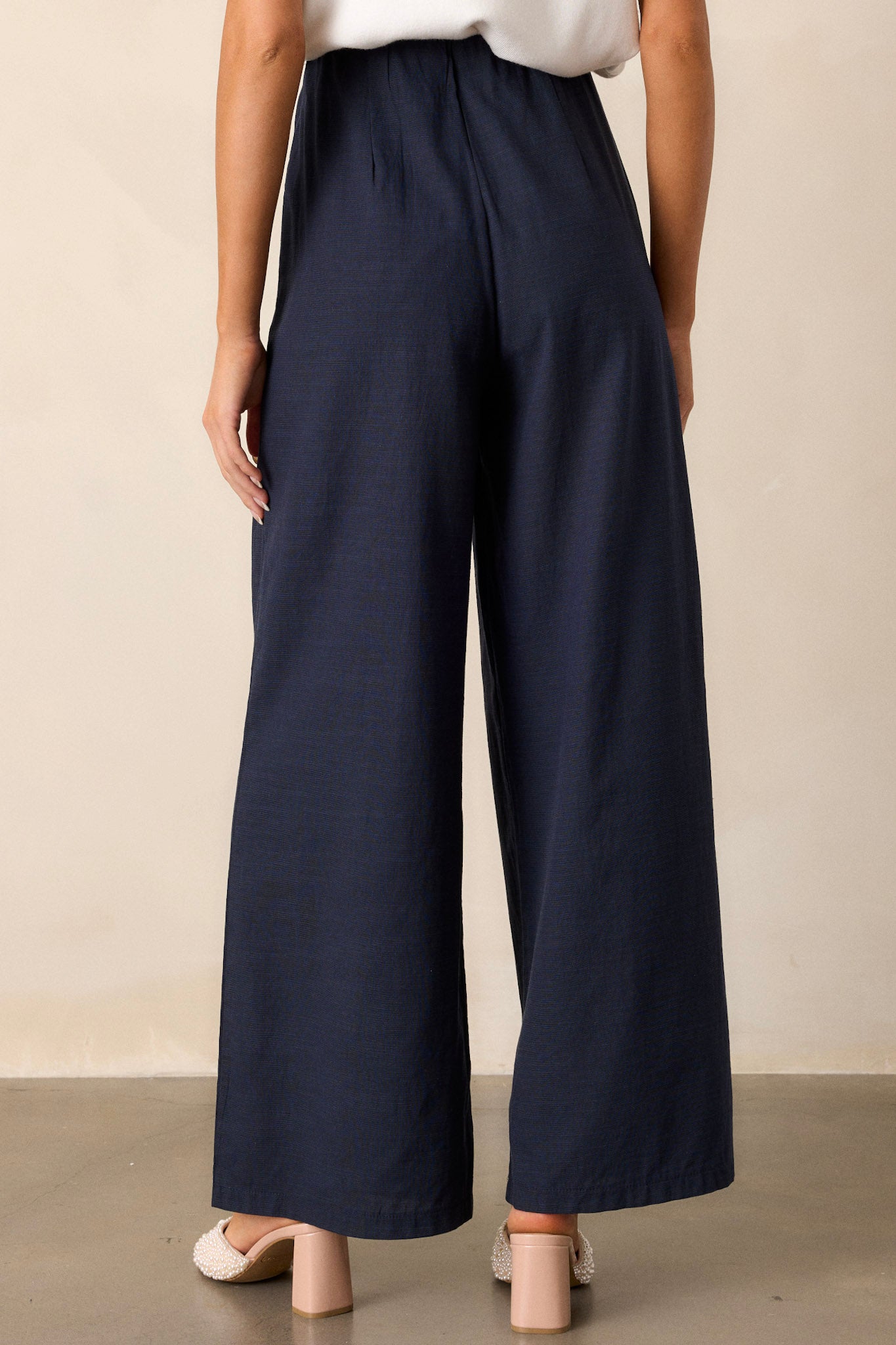 Back view of navy straight leg pants highlighting the high waisted design and the straight leg cut.