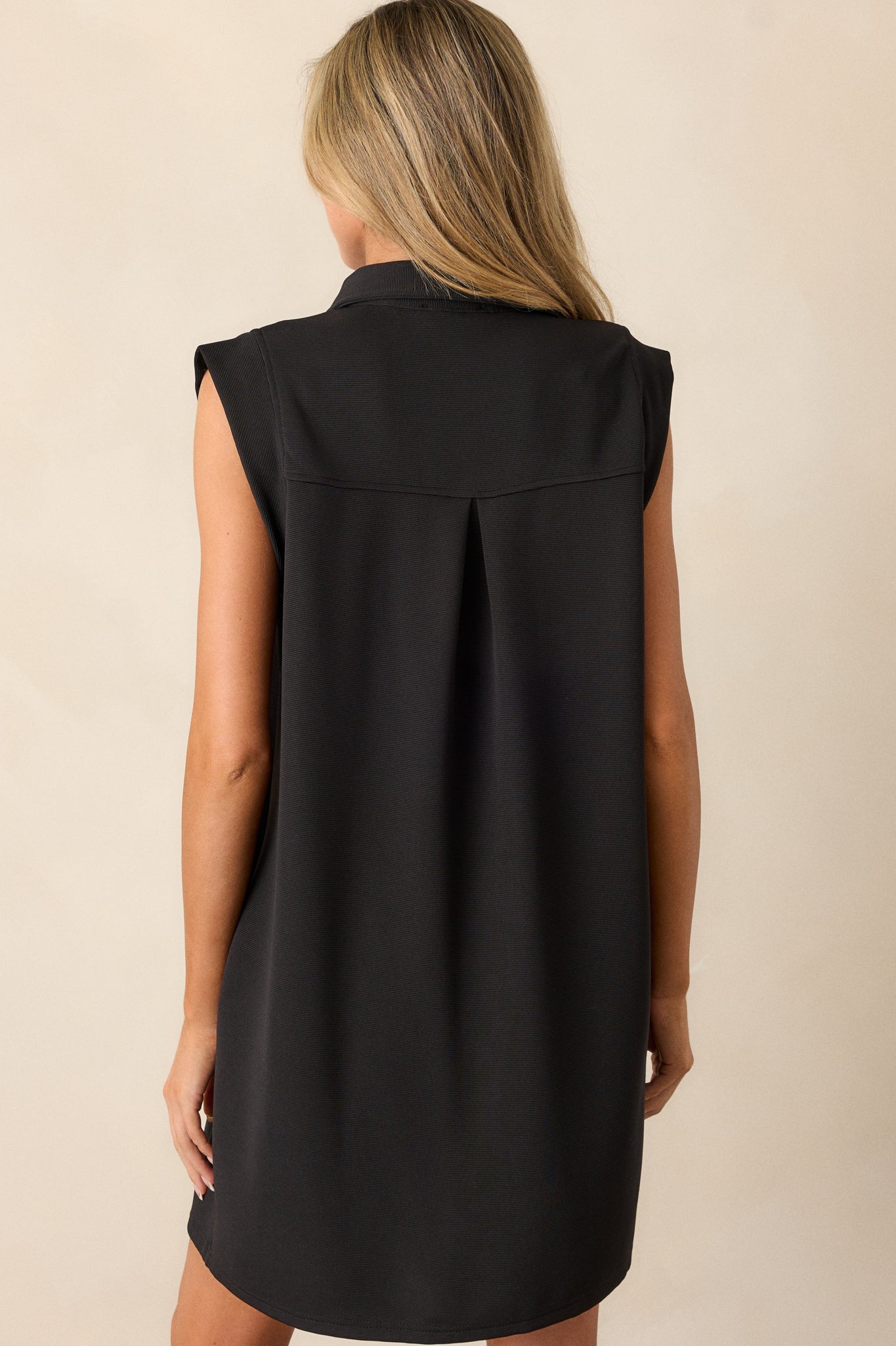 The black mini dress shown from the back, highlighting the sleeveless design and overall relaxed fit.