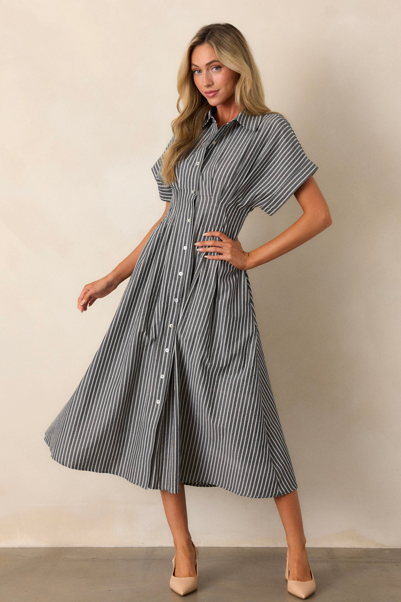 A side view of a black dress with a collar neckline, button-front detailing, and short sleeves, featuring a subtle stripe pattern across the top.