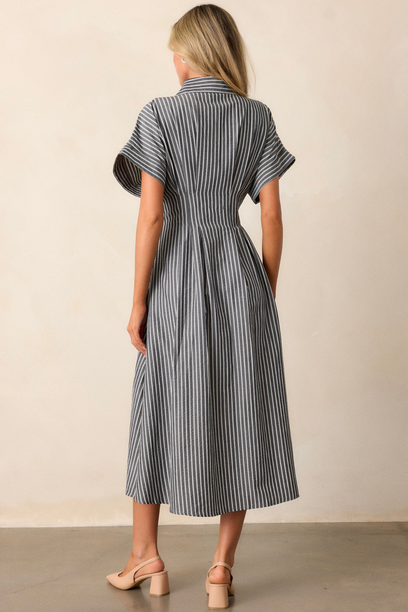 Back view of the black dress, showcasing the continuation of the stripe pattern and the structured fit of the short sleeves and collar.