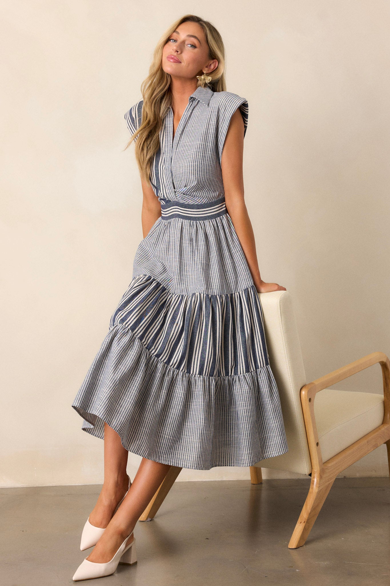 Navy dress with a collared neckline, featuring built-in shoulder pads and a mixed stripe pattern, buttoned down the front with cap sleeves.