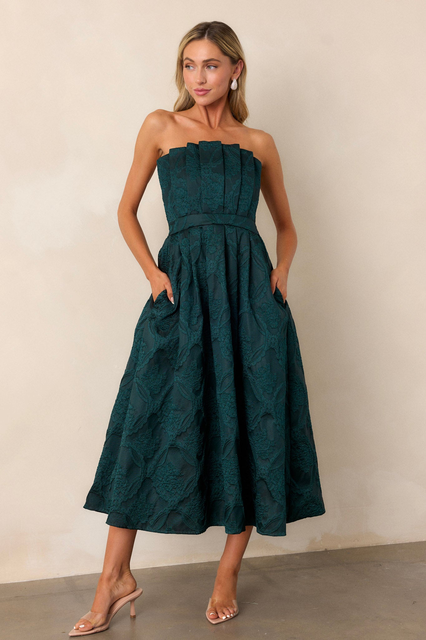 Front view image of the green dress, highlighting the functional hip pocket and the detailed pleating on the bodice.