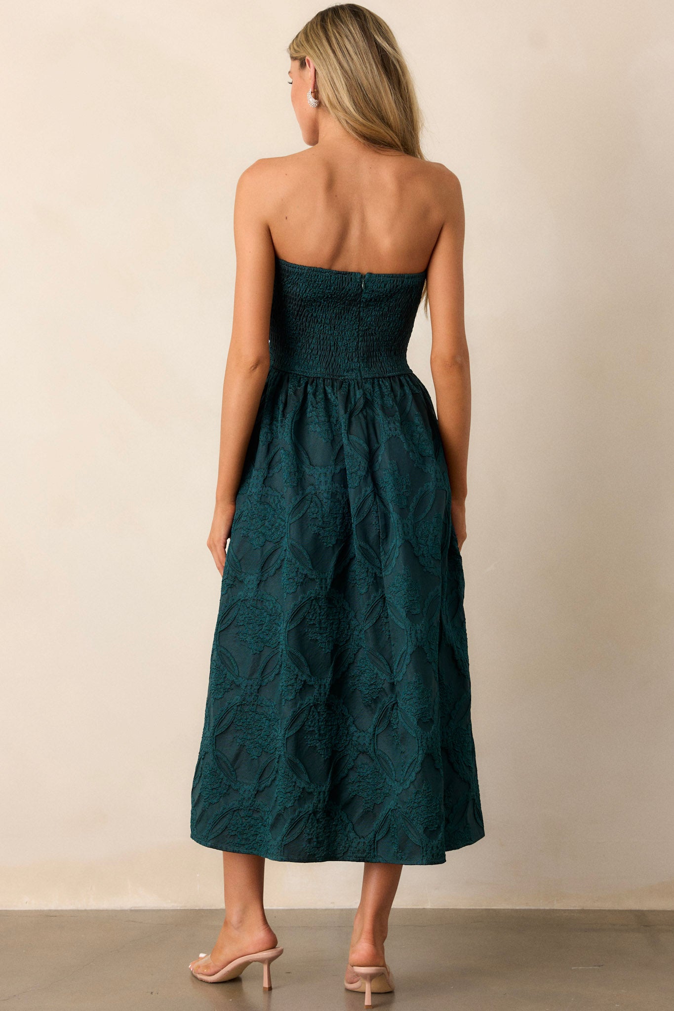 Back view of the green dress, focusing on the smocked back panel and the discrete zipper along the back of the strapless design.