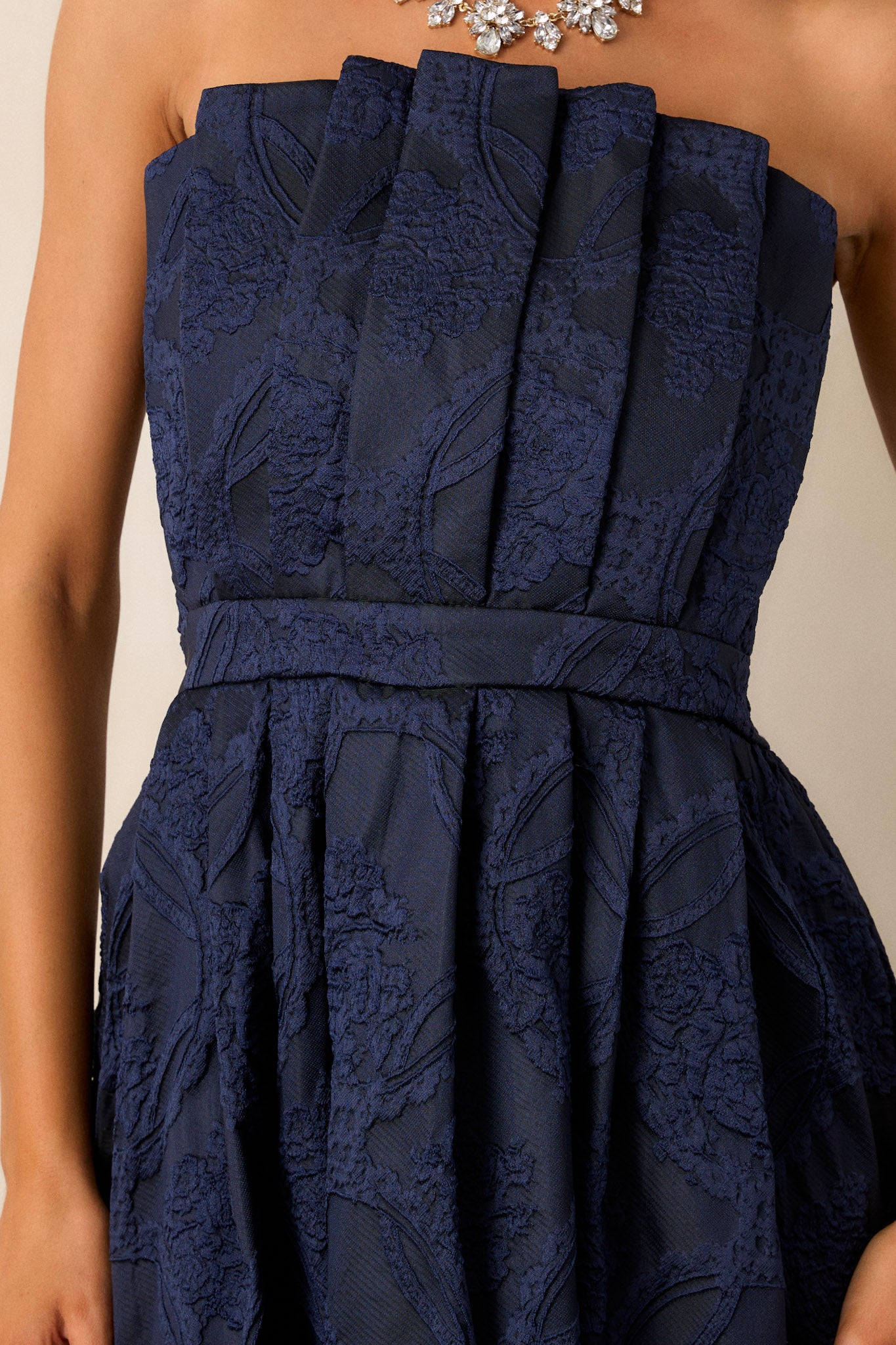 Close up of the pleated, jacquard bodice on this strapless, navy, midi dress. 