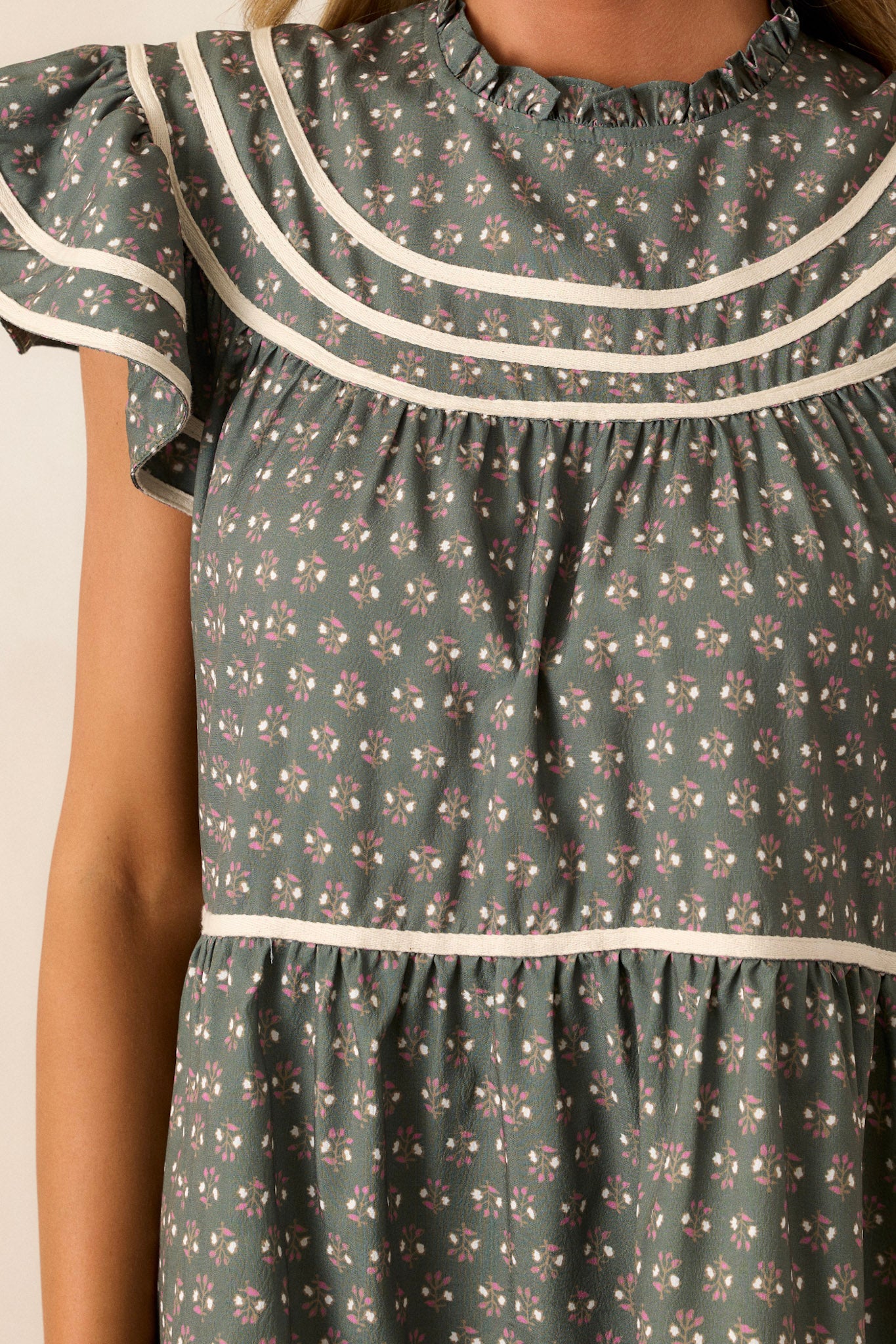 Close-up of the fabric texture, highlighting the dainty floral print and fine details on the high ruffle neckline.