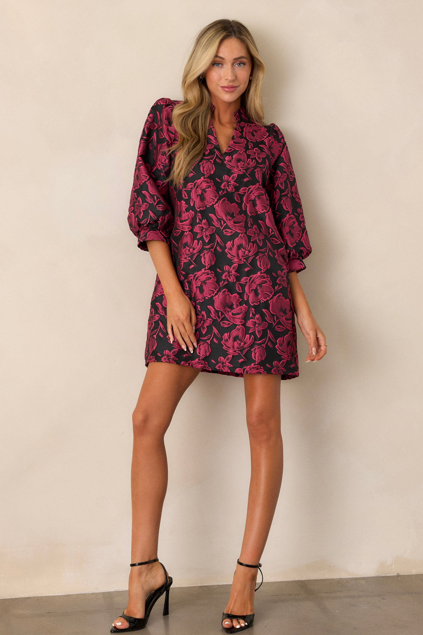 The same dark fuchsia mini dress from a full-length angle, showcasing the flow of the balloon sleeves and the floral jacquard pattern on the front of the dress.