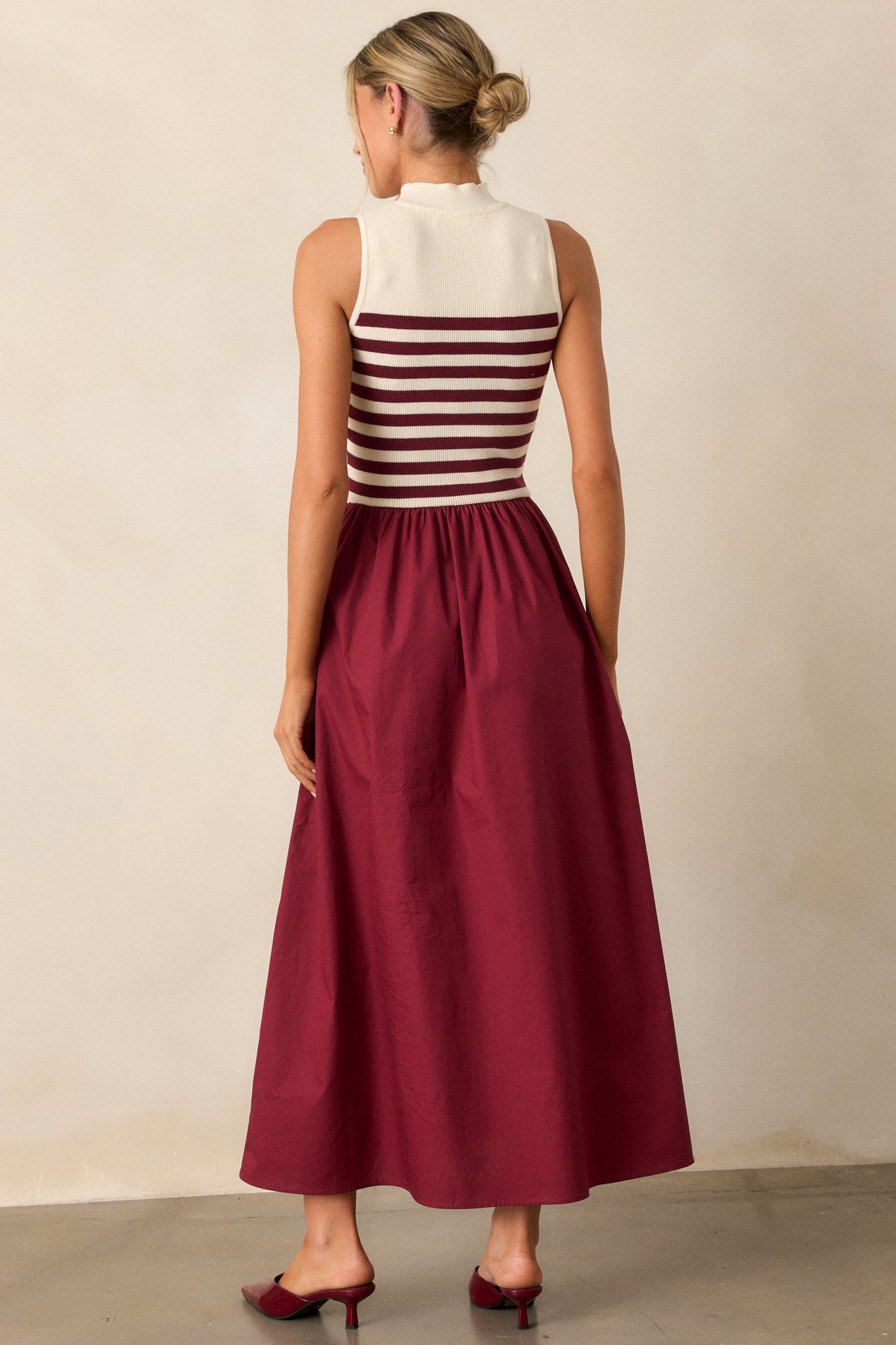 Back view of this burgundy dress featuring a sleeveless striped top and a solid full-length skirt.