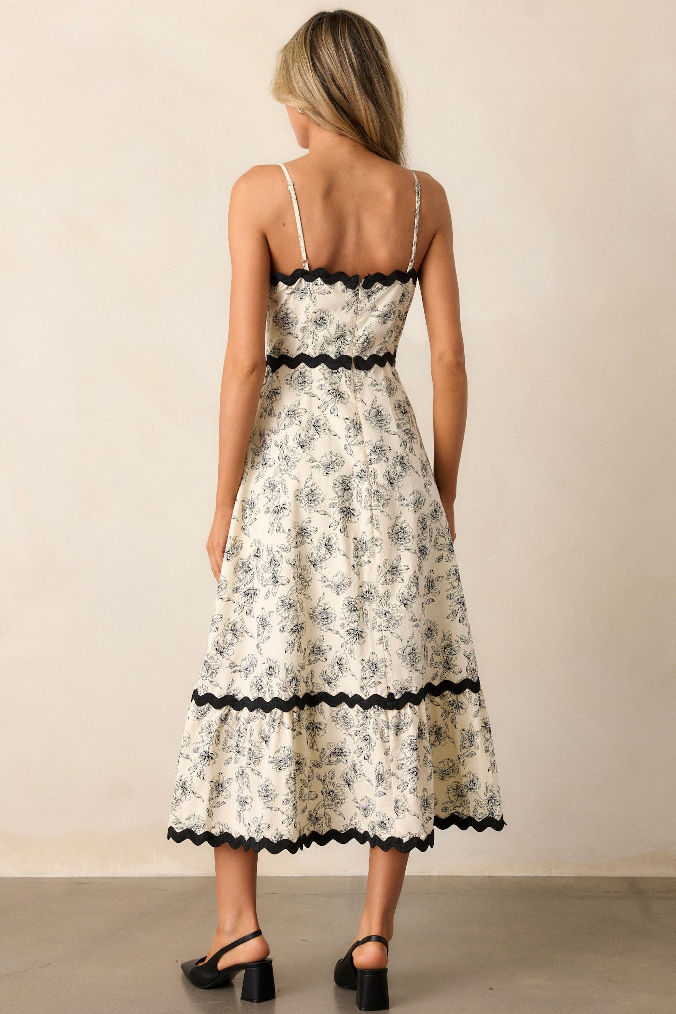 Back view of the ivory maxi dress highlighting the discrete back zipper, the tiered design, and the black ruffle trim on the straps.