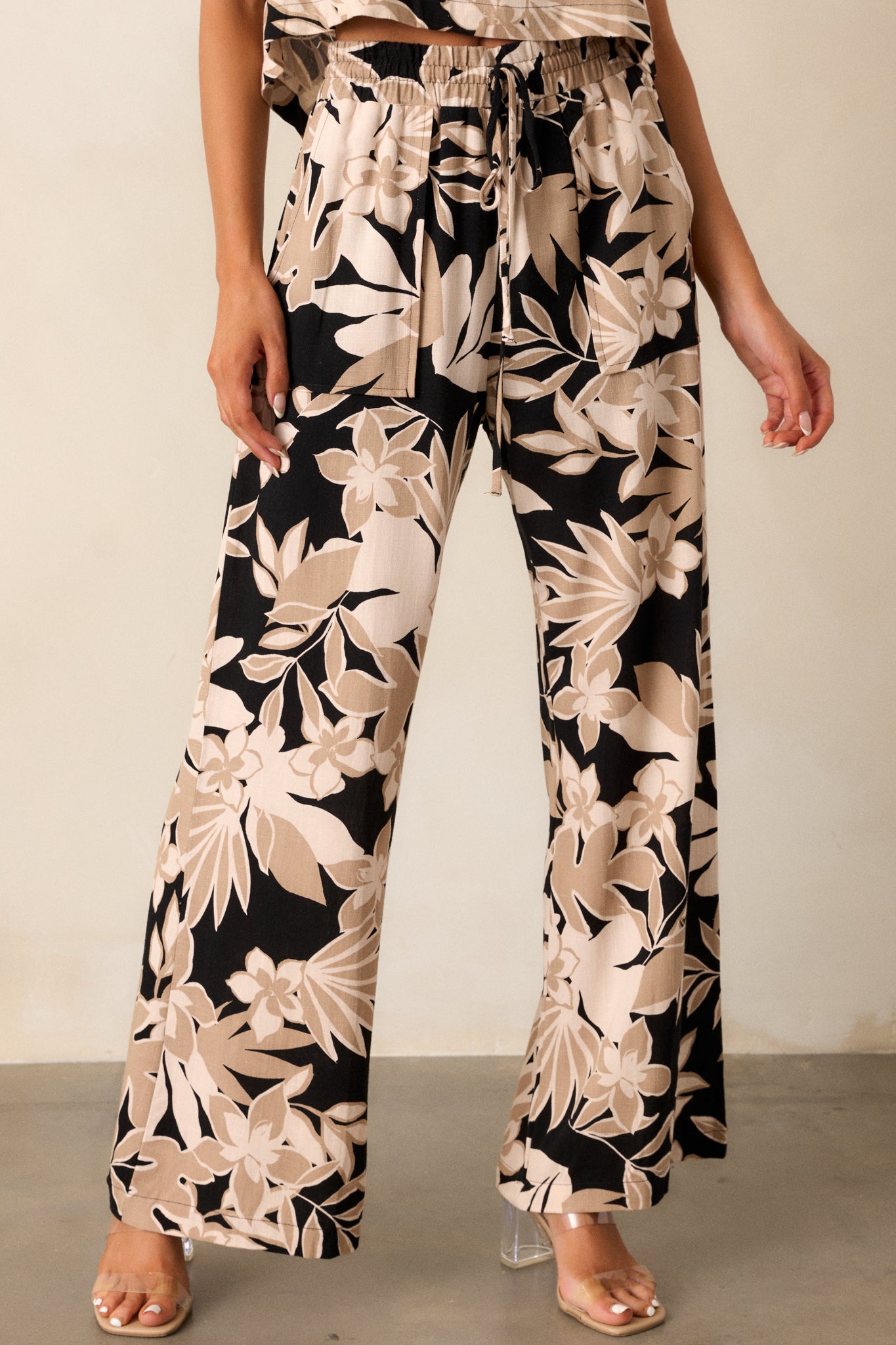 Cropped image of the taupe pants, focusing on the elastic waistband and high waist with floral pattern detail.