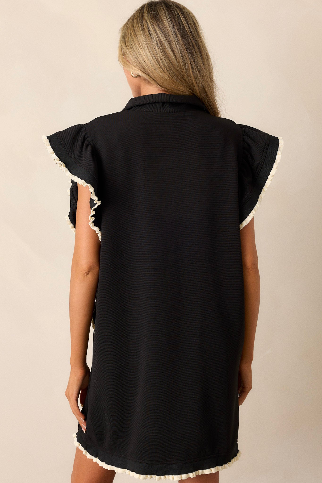 A back view of the dress, highlighting the clean lines of the back and the overall fit, while also showcasing the flutter sleeves from behind.