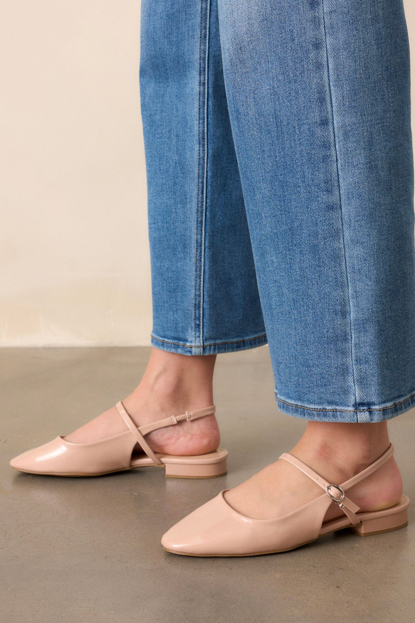 These beige flats feature a slightly squared toe, an across the foot strap with a silver buckle, an ankle strap, a small platform, and a shiny beige finish.