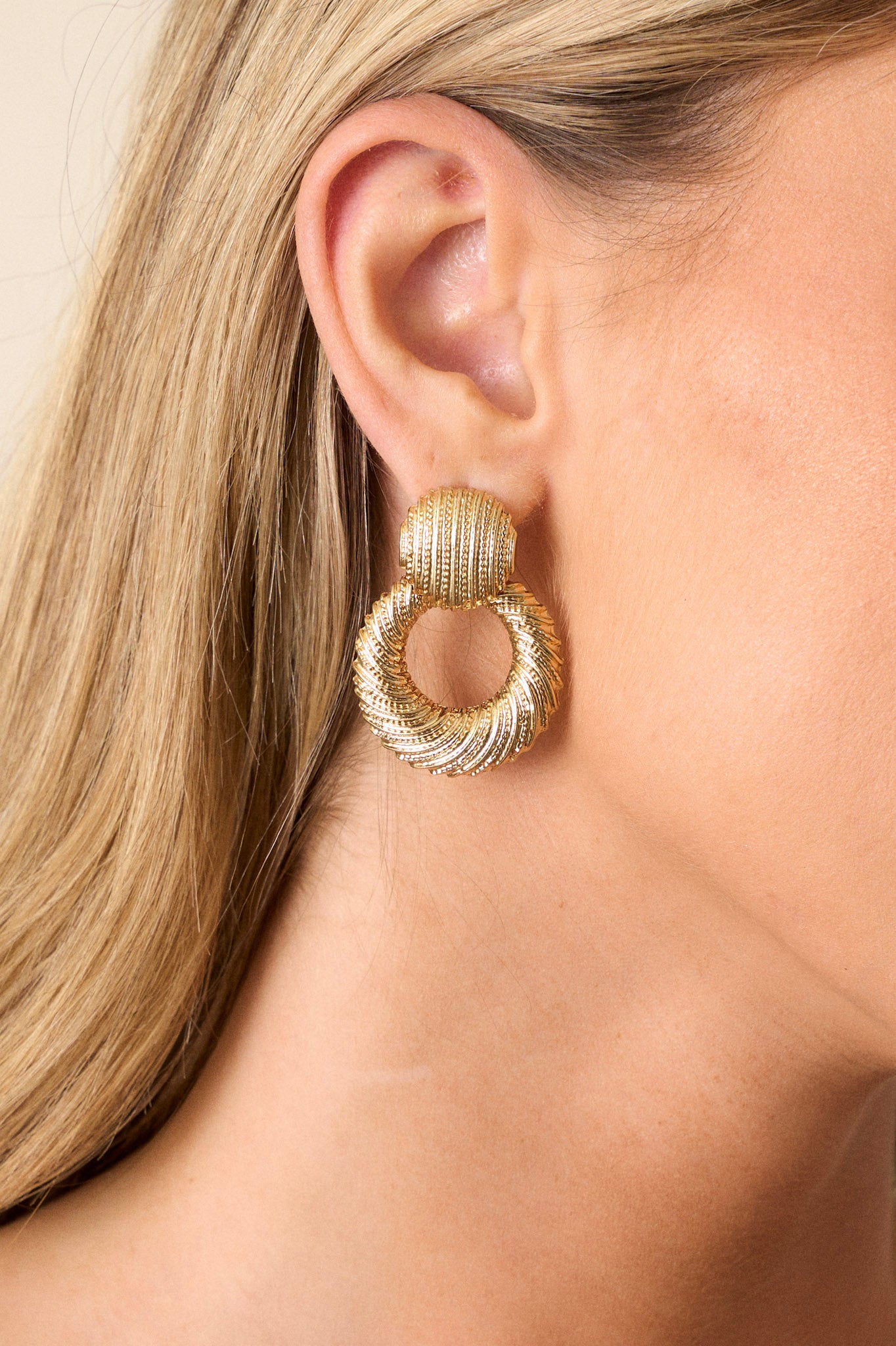 Front view of these earrings that feature textured gold hardware, a textured stud with attached hoop, and secure post backings.