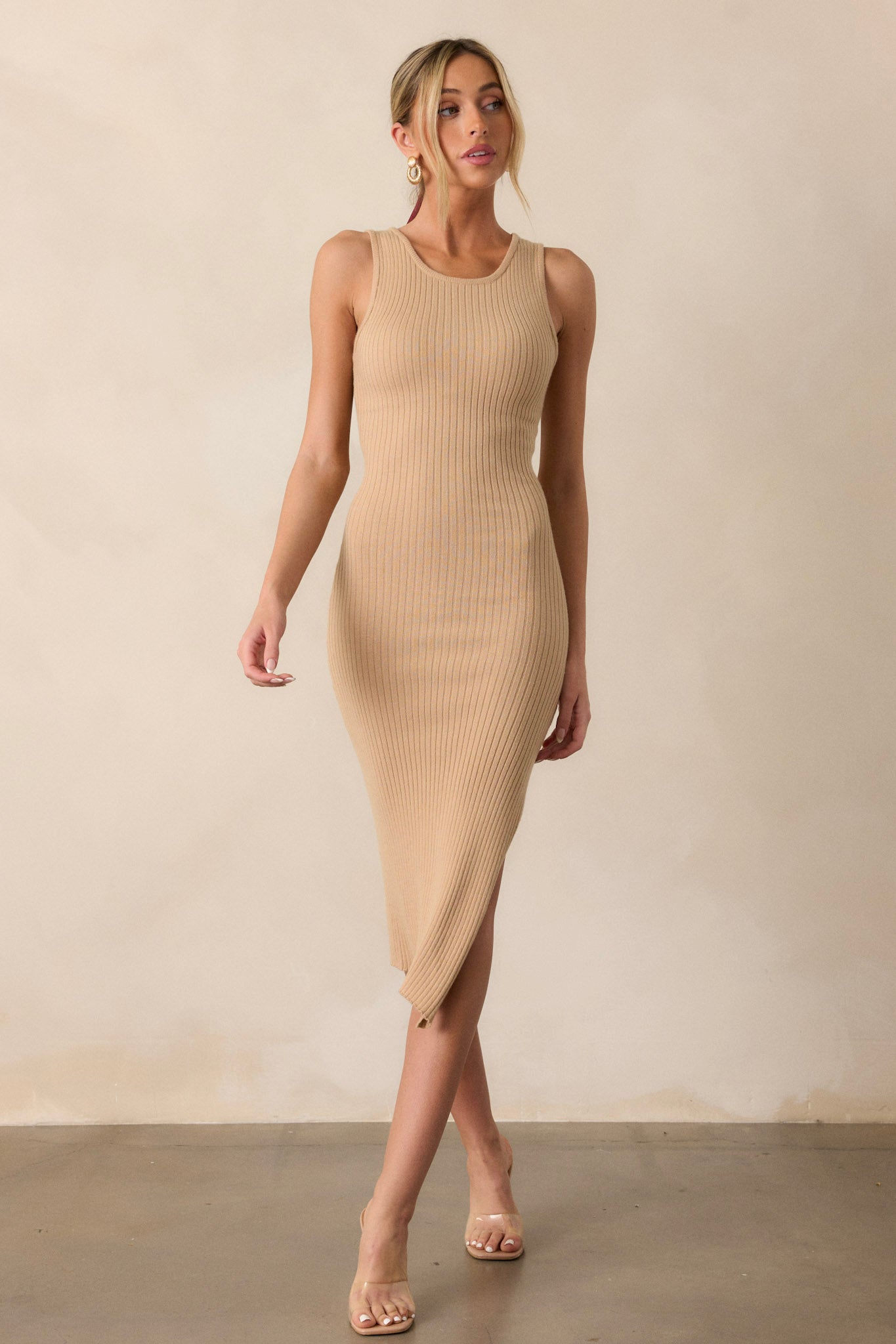 Movement view of of this taupe bodycon dress that features a high crew neckline, a ribbed material throughout, a slit up the leg and a sleeveless design