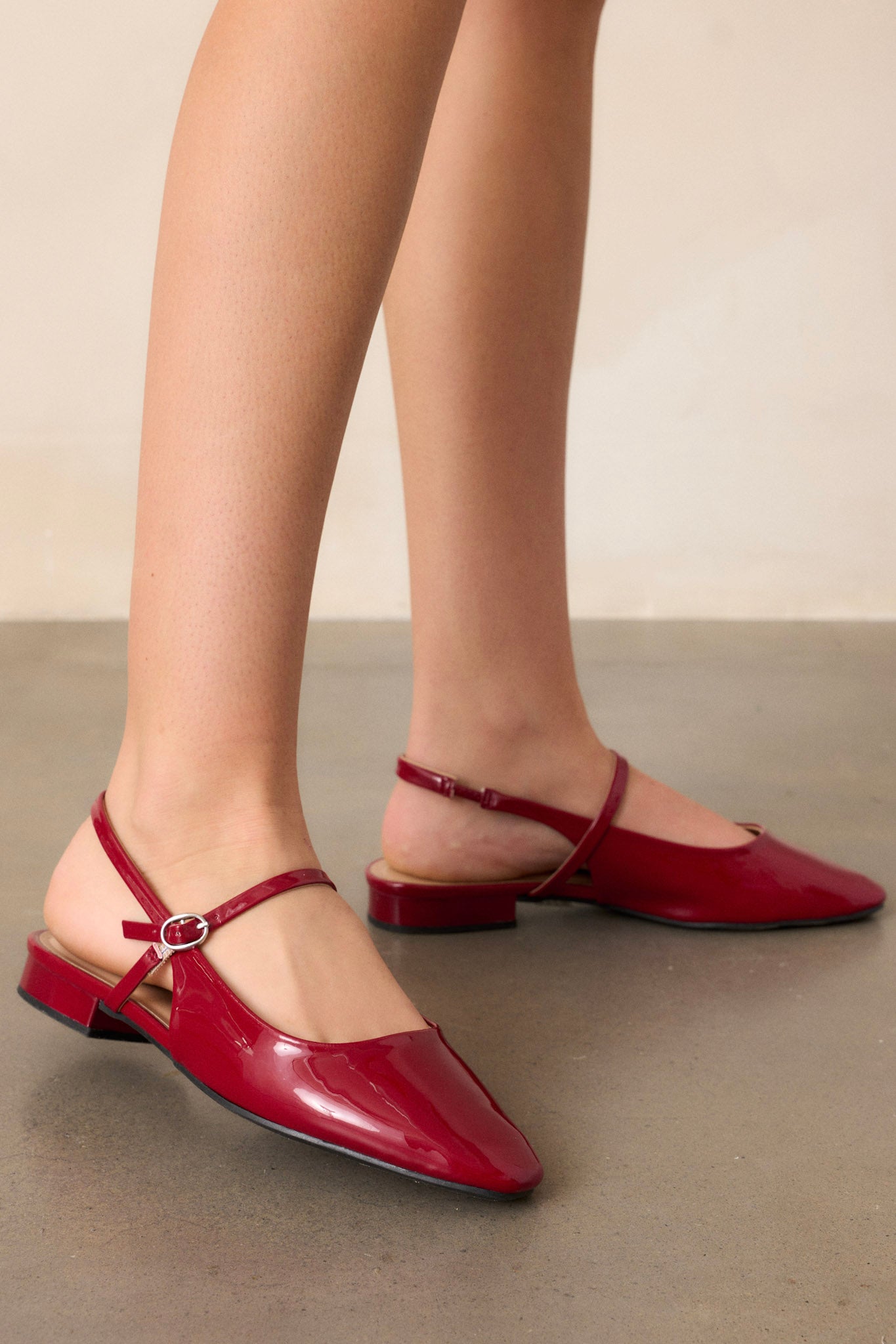 These red flats feature a slightly squared toe, an across the foot strap with a silver buckle, an ankle strap, a small platform, and a shiny beige finish.