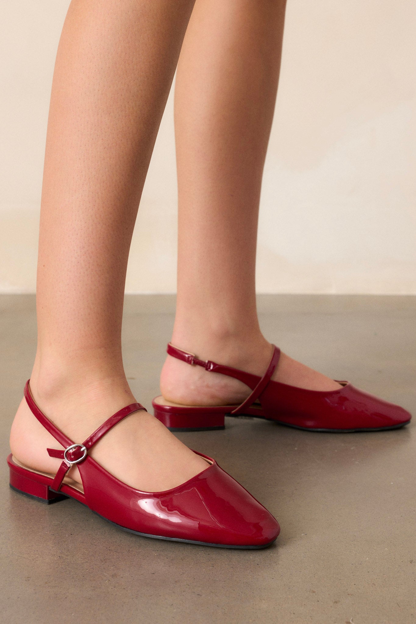 Close-up view of the burgundy flats, showcasing the slightly squared toe and the across-the-foot strap with a shiny silver buckle.