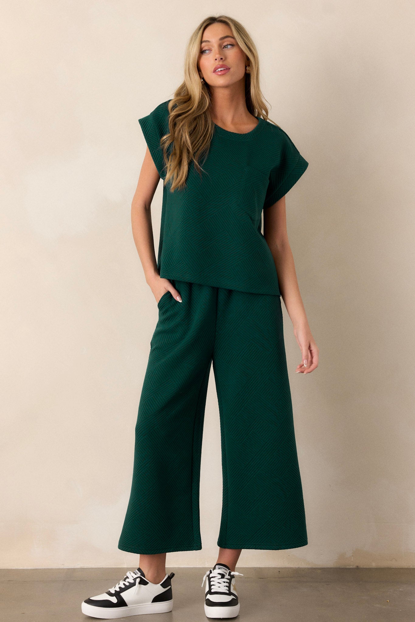 Full length view of pants featuring a high waisted design, an elastic waistband, functional hip pockets, a textured crisscross design, and a wide leg