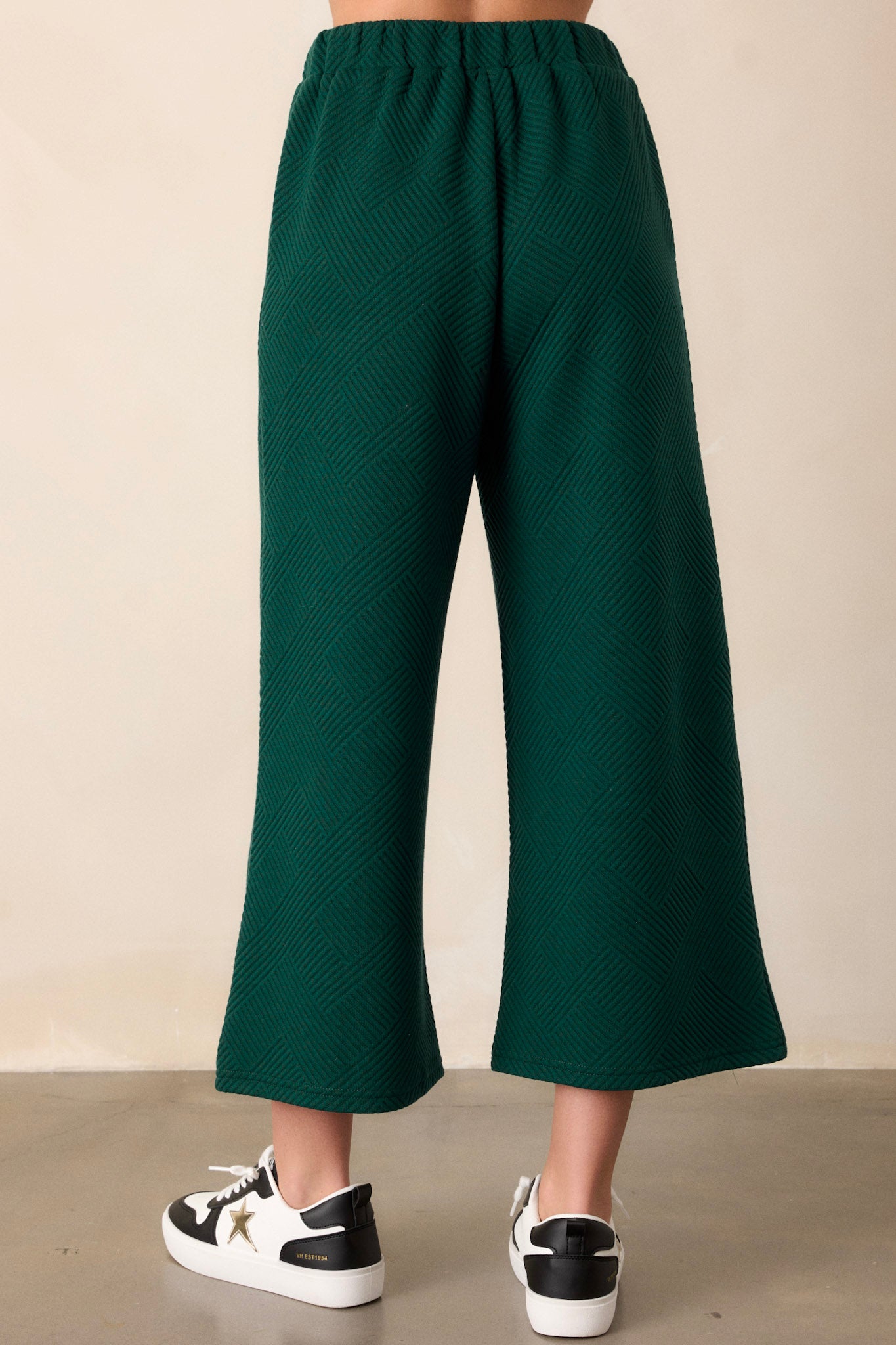 Back view of the pants highlighting the continuation of the textured crisscross design, the wide leg cut, and the smooth elastic waistband.