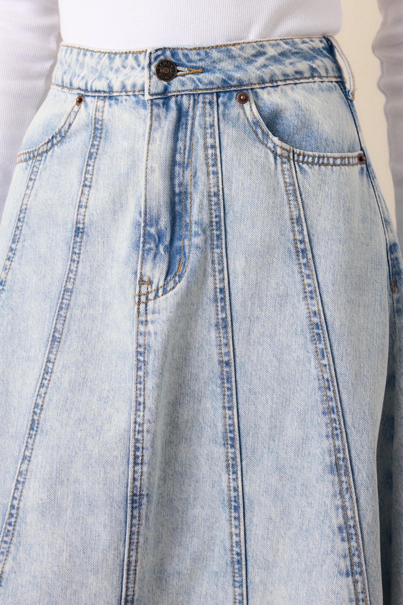 A closer view of the waist area, focusing on the button zipper closure and the clean stitching along the waistband.