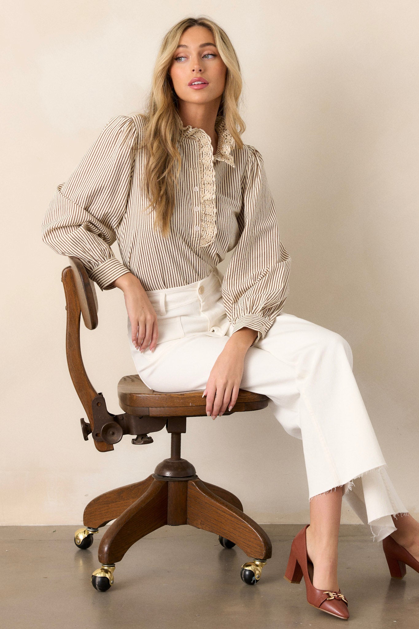 Side view of this brown stripe top that features a lace collar, a functional button front bust, a vertical stripe pattern, brown and ivory stripes and puffed long sleeves.
