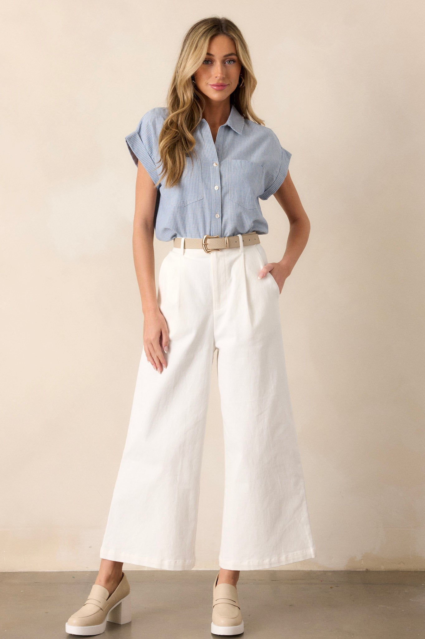 Full body view of this light blue stripe top that features a collared v-neckline, a functional button front, a vertical stripe pattern, functional bust pockets, and cuffed short sleeves.