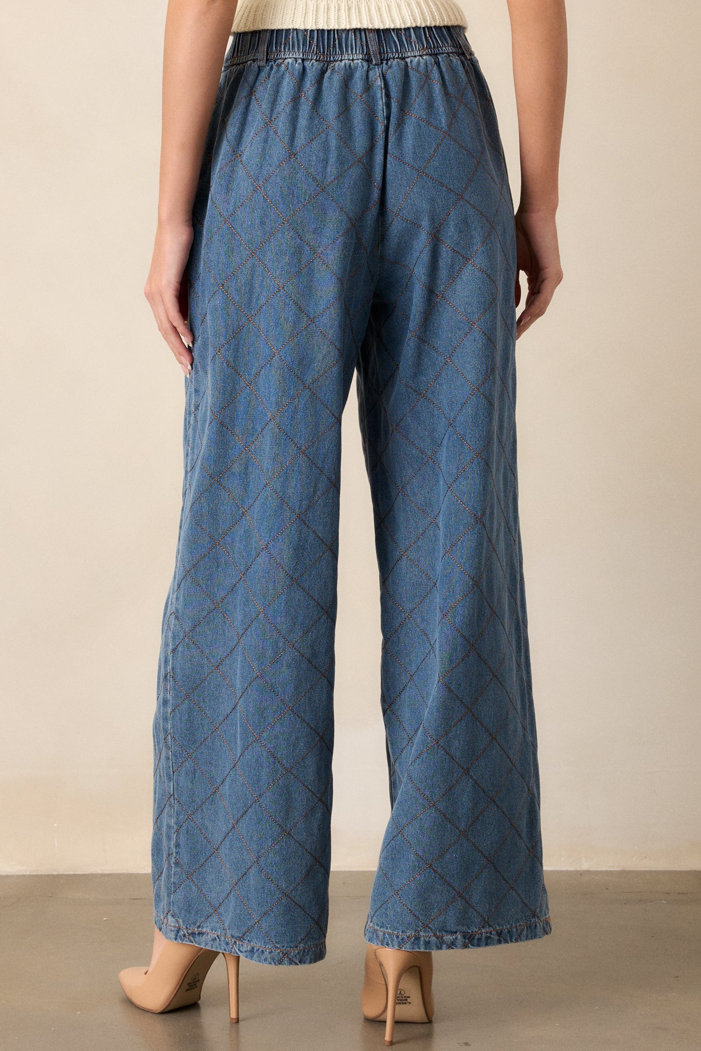 Back view of quilted jeans featuring a high waisted design, a hook and bar closure, functional belt loops, hip pockets, a quilted design and a wide leg.