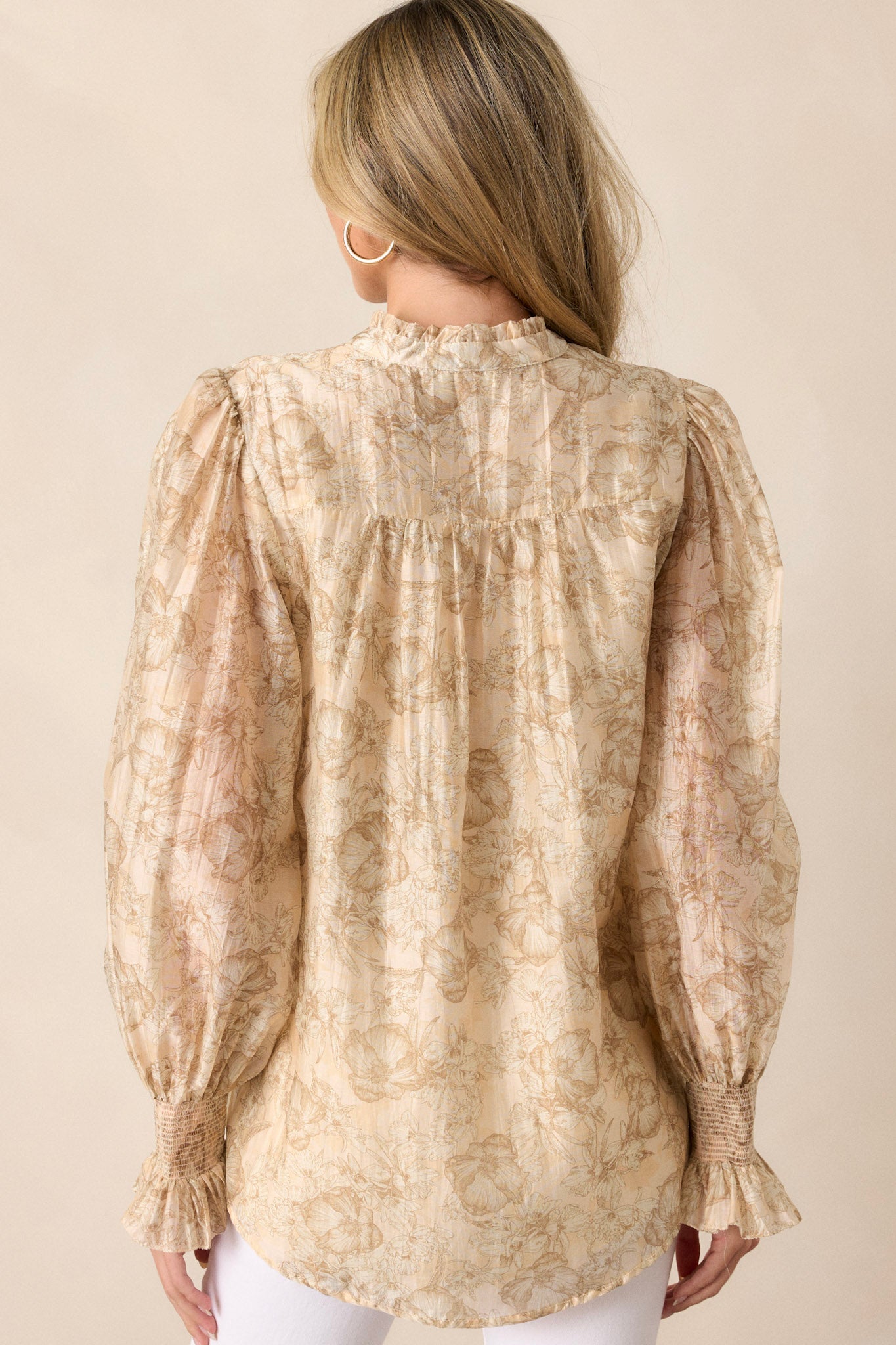 Back view of the beige top, showing the continuation of the floral design and the high pleated ruffle neckline from the rear.