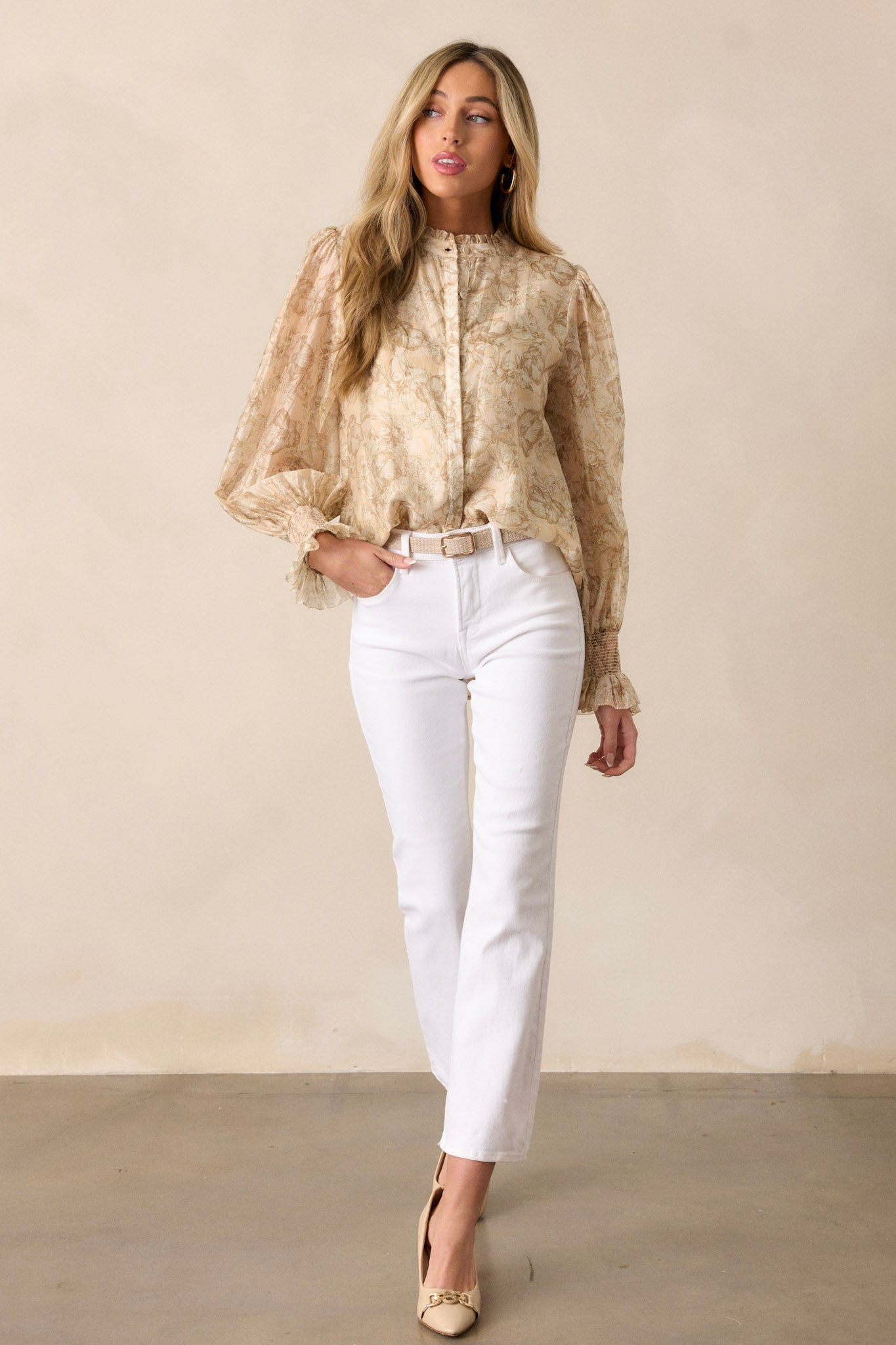 Front view of the beige top, highlighting the functional button front, high ruffled neckline, and floral pattern.