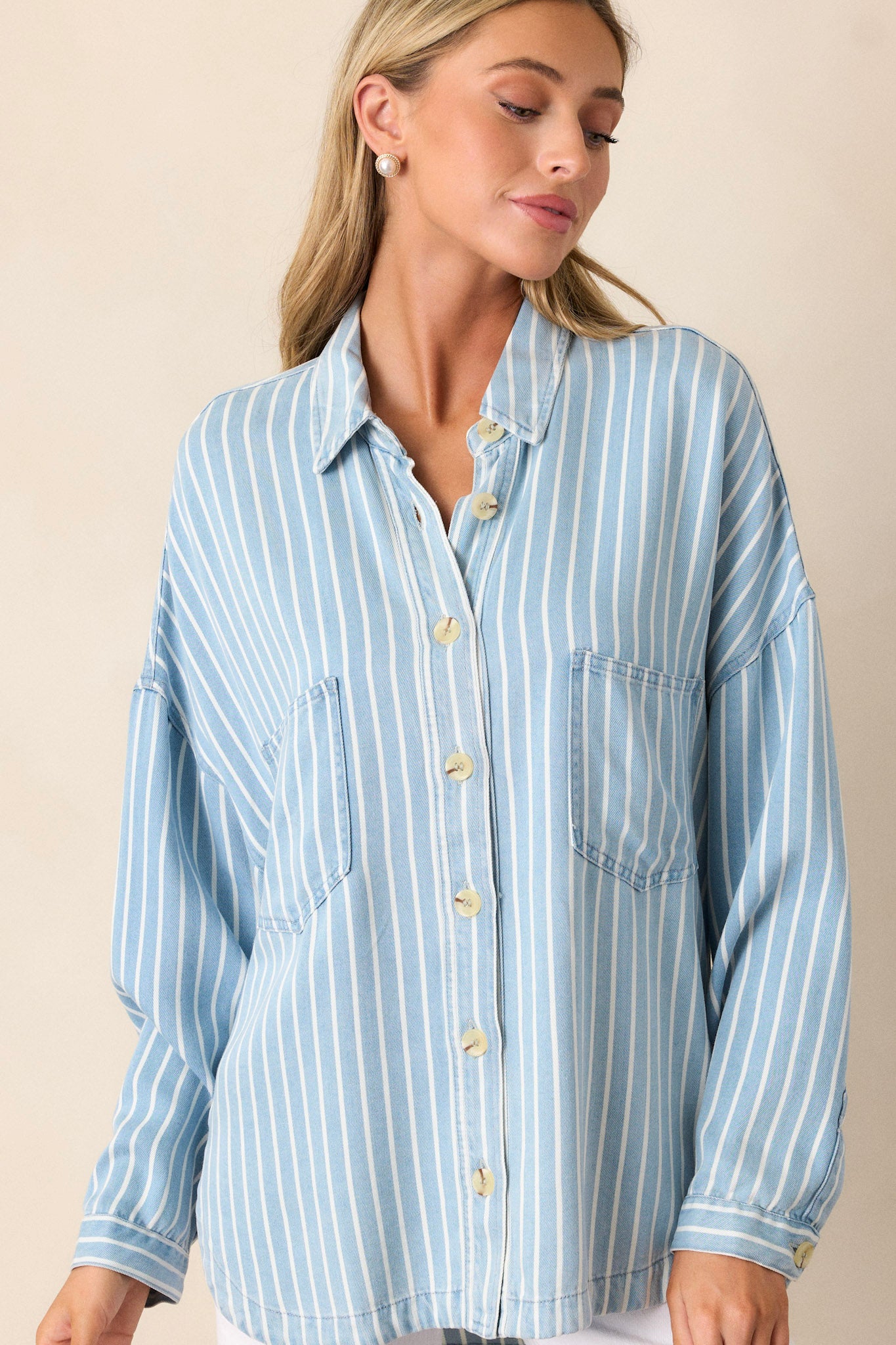 Front view of a top featuring a collared neckline, functional buttons down the front, two functional bust pockets, long sleeves with buttoned cuffs, a scoop bottom hem, and a super soft material.