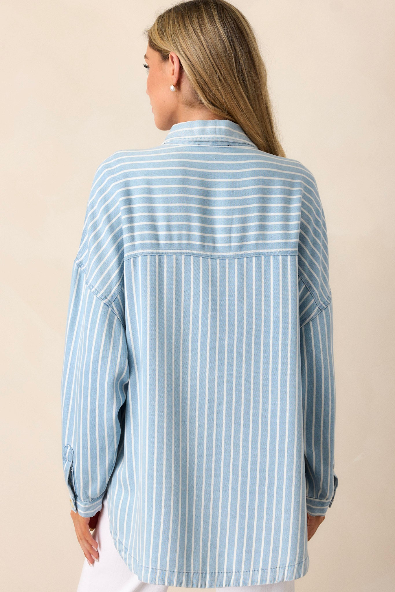 Back view of a top highlighting the long sleeves with buttoned cuffs, a scoop bottom hem, and the super soft material.