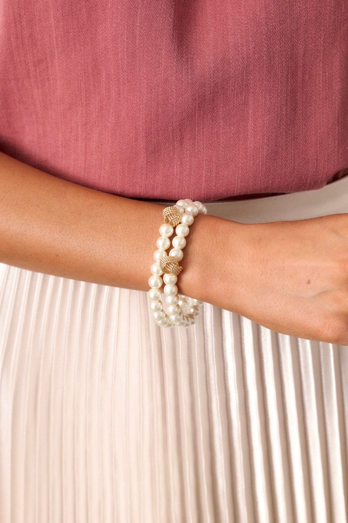 This bracelet set features ivory pearls, gold textured rings, and elastic bands underneath.