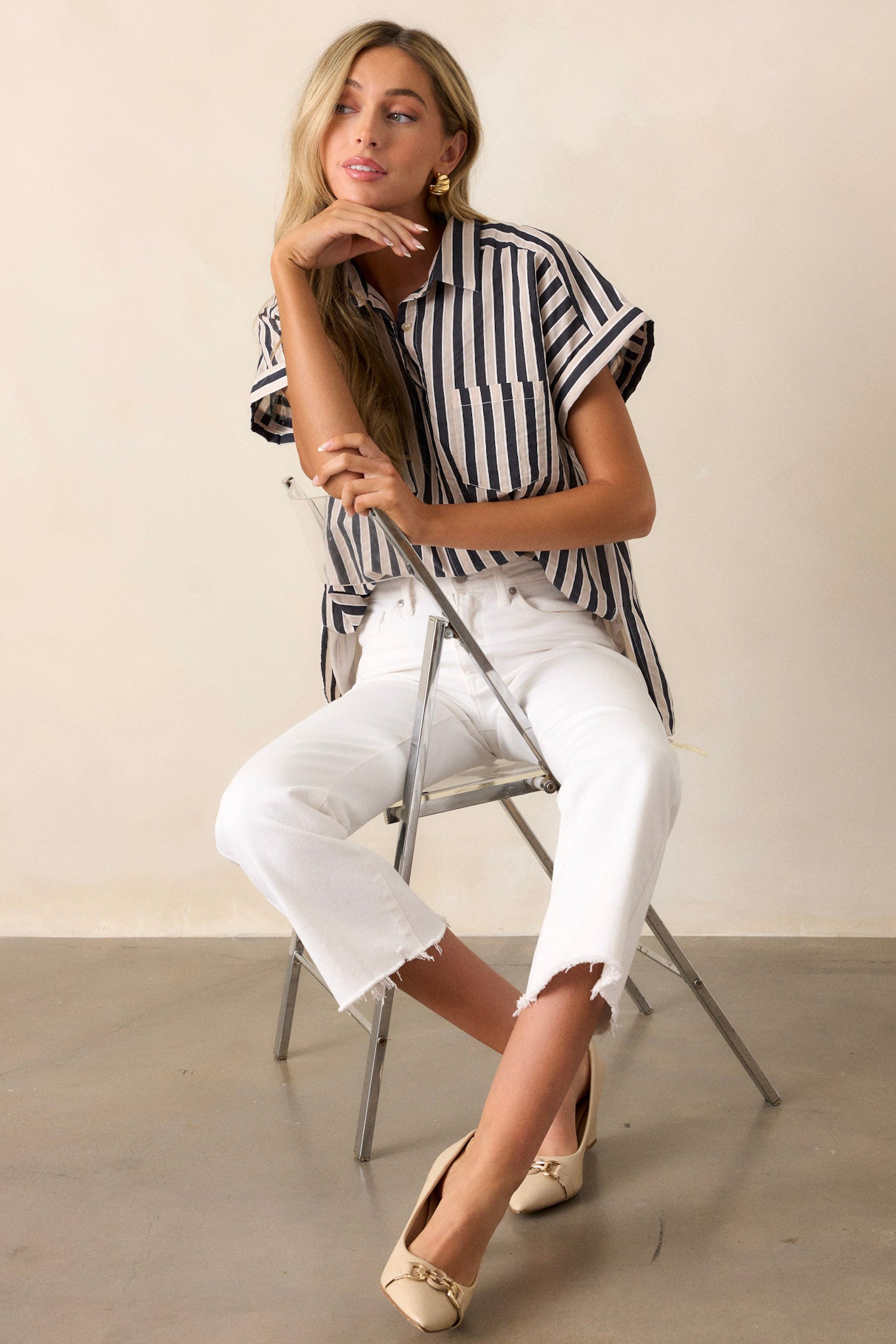 Full length view of a black stripe top with a collared neckline, a full button front, functional breast pockets, a vertical stripe design, cuffed short sleeves, and a split scooped hemline