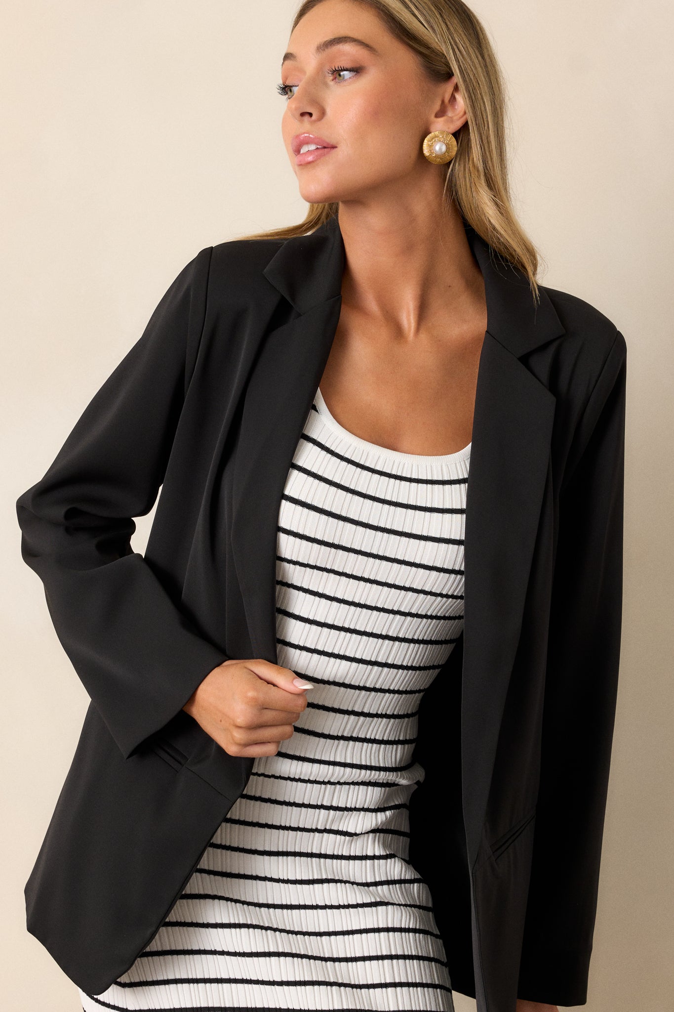 An angled action shot of the black blazer showcasing its lightweight shoulder pads, lapel collar, and sleek design.