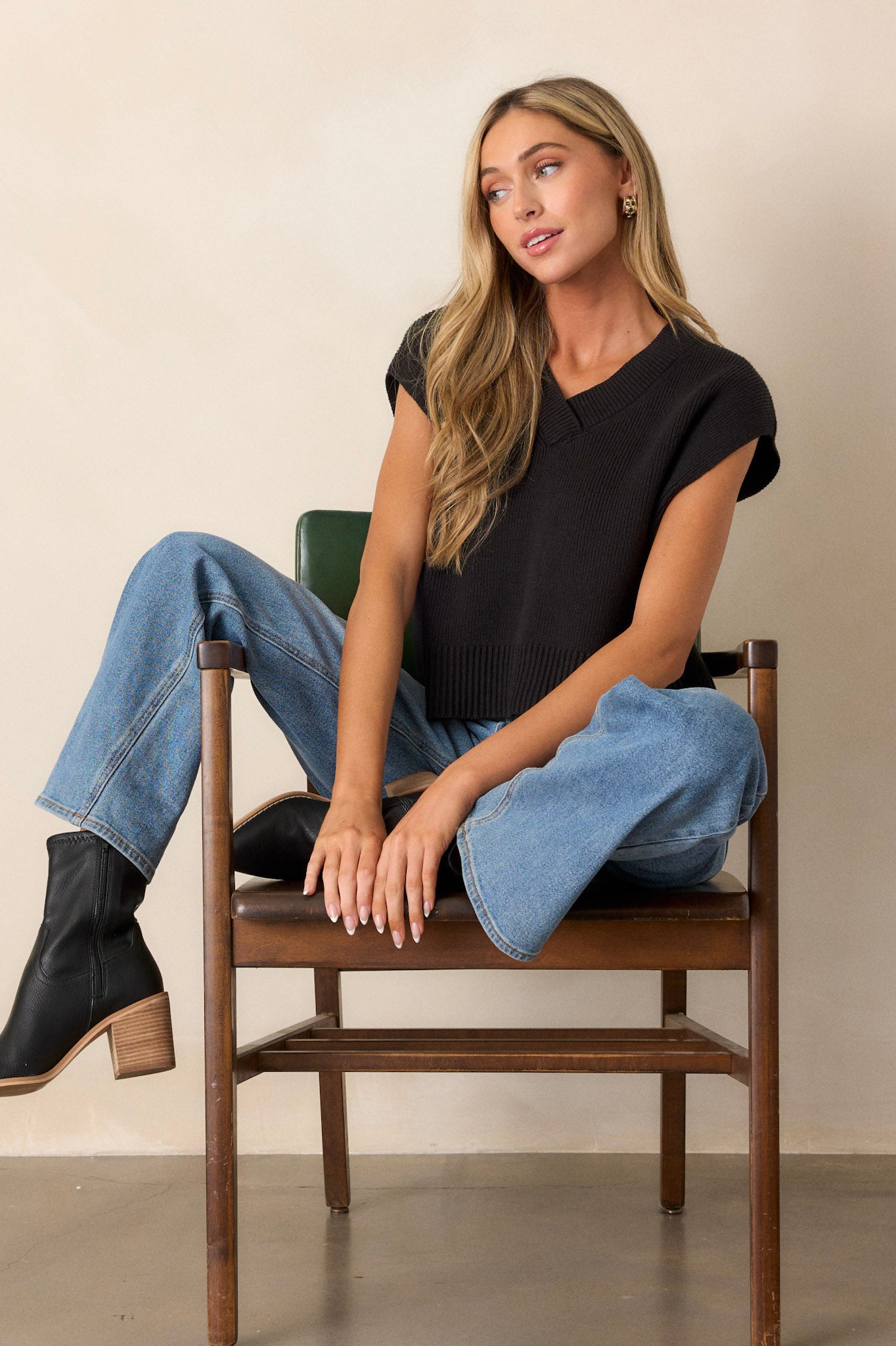 Full body view of a black sweater top with a v-neckline, a knit material, a thick hemline, side slits in the hem, and short sleeves