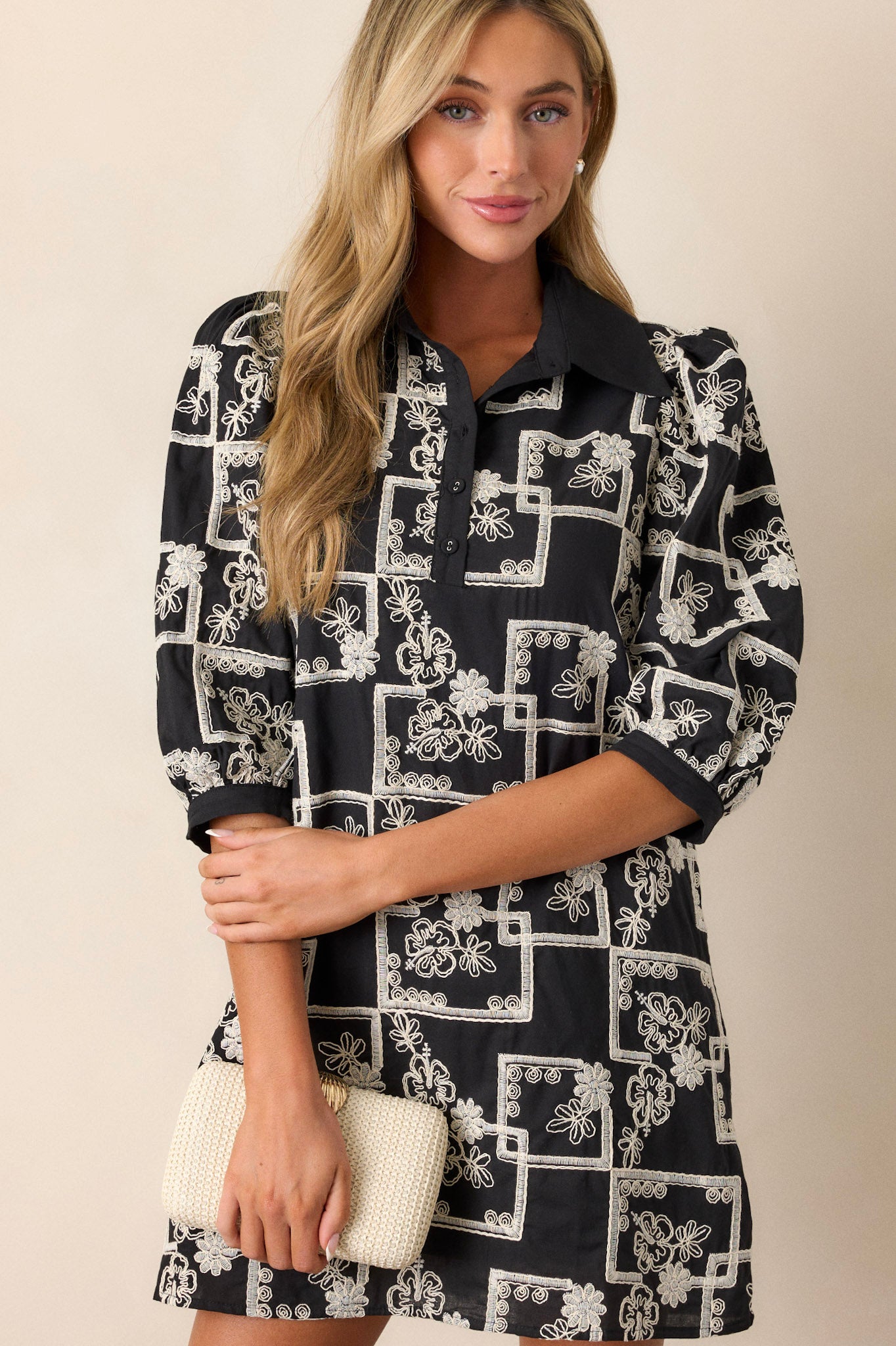 This dress features a collared neckline, a functional button up bust, a white embroidered floral and square pattern, a relaxed fit and puffed half sleeves.