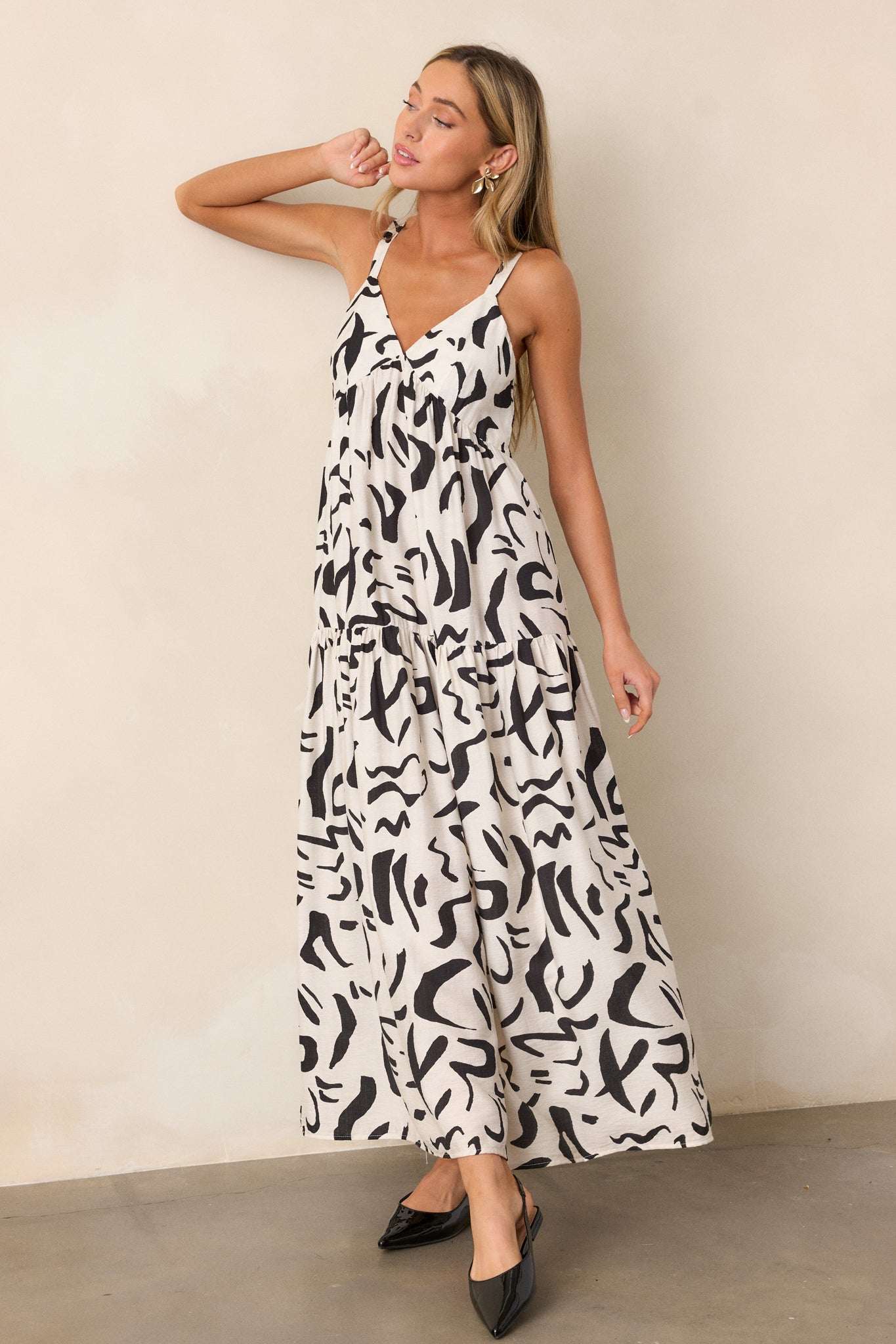 Full view of the white dress, highlighting the v-neckline, black abstract design, and tiered maxi cut.