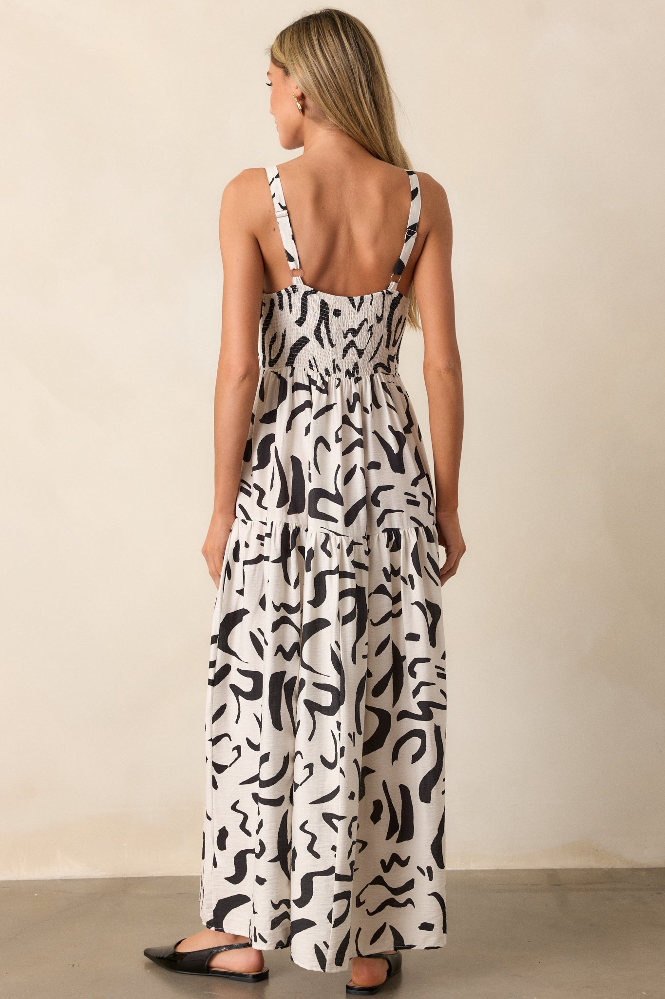 Back view of the dress, showing the smocked back, adjustable straps, and the layered tiered design that flows to maxi length with the black abstract pattern throughout.