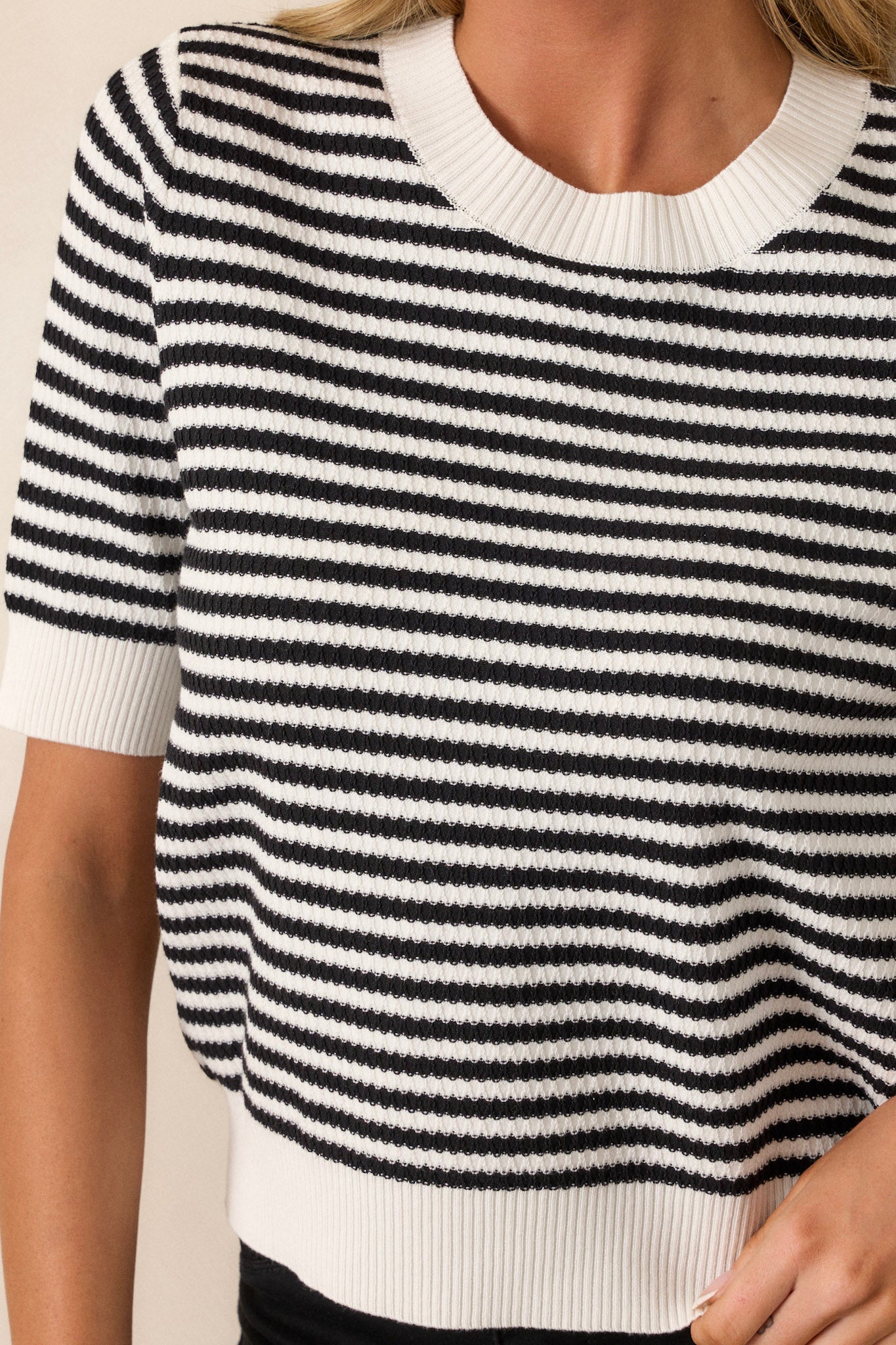 A focused view of the ribbed crew neckline, showcasing the fine knit and how it complements the stripe pattern for a polished appearance.