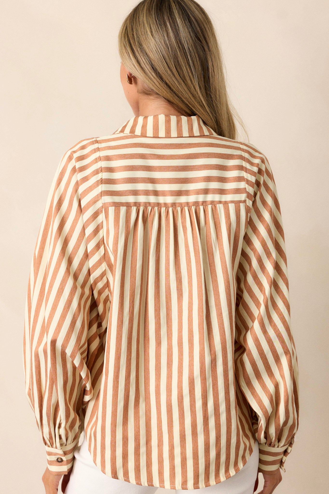 Back view of the tan stripe top highlighting the vertical stripe design and the cuffed dolman long sleeves.