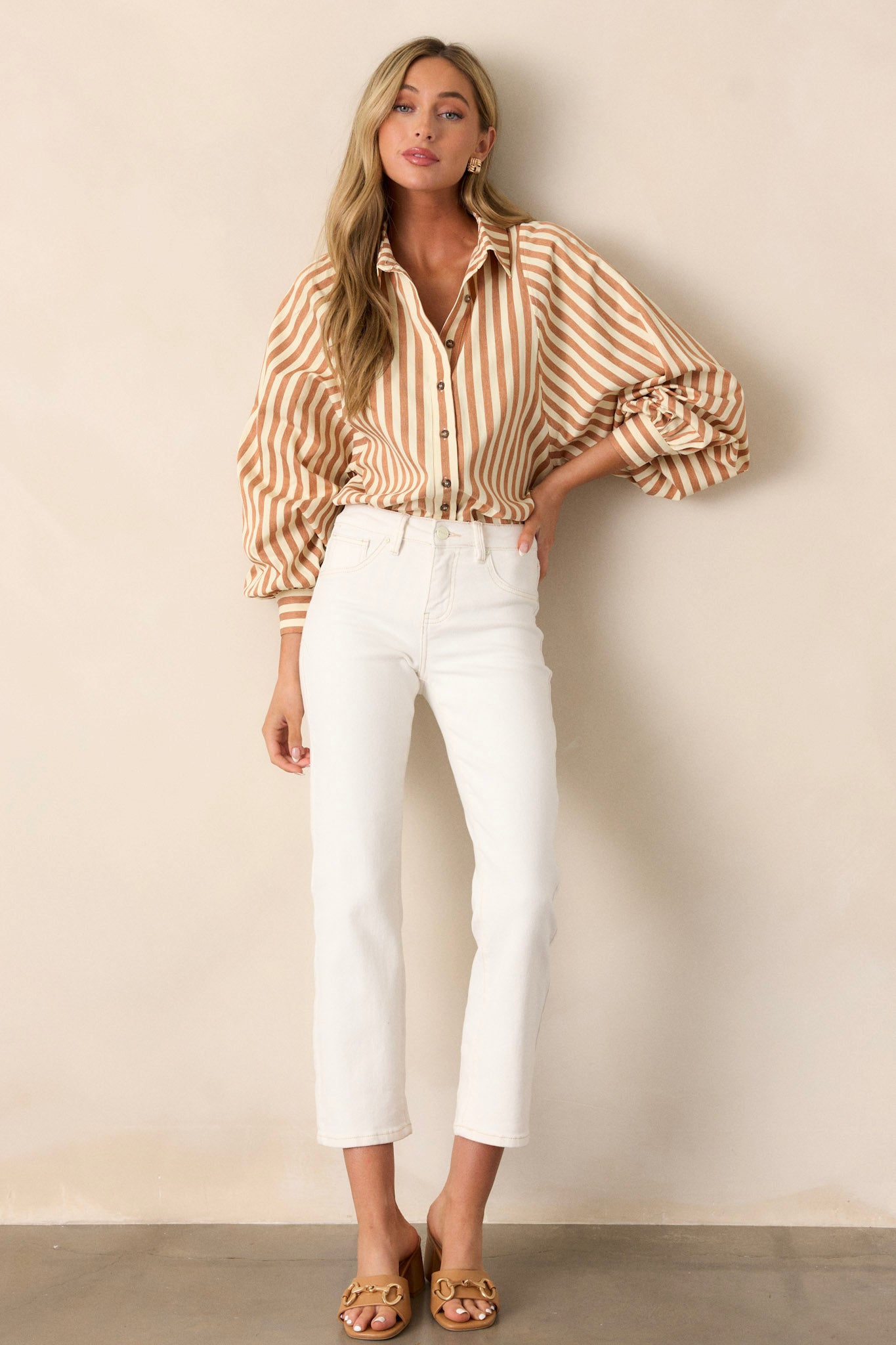 This tan stripe top features a collared neckline, a functional button front, a vertical tan and white stripe design and cuffed dolman long sleeves.